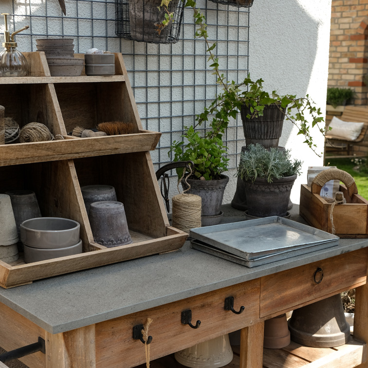 Holz-Gartentisch mit Pflanzwerkzeugen und Tontöpfen in natürlichen Farben, Gartenarrangement