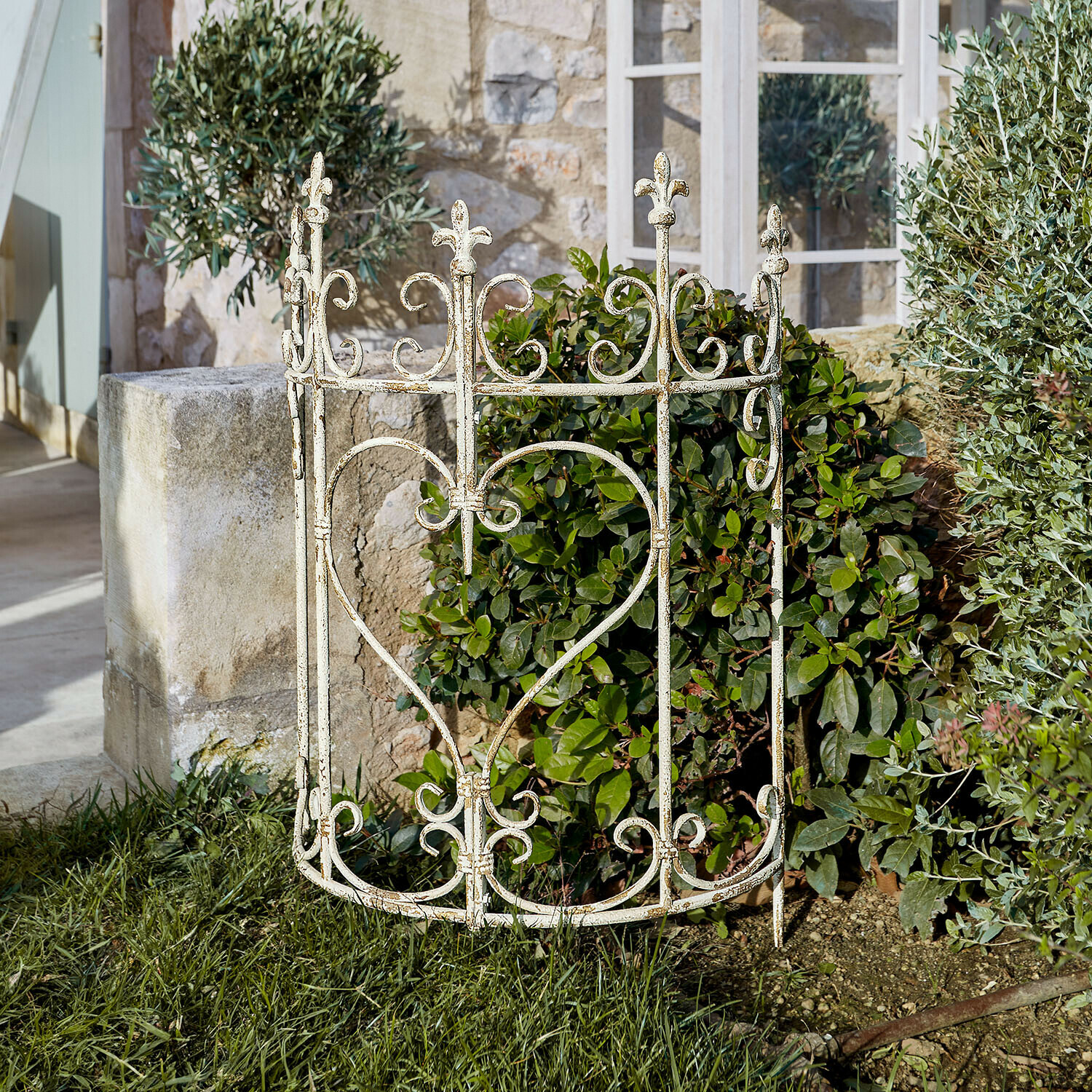 Weißer Metall-Gartenzaun mit Herzmotiv und floralen Verzierungen auf grünem Rasen