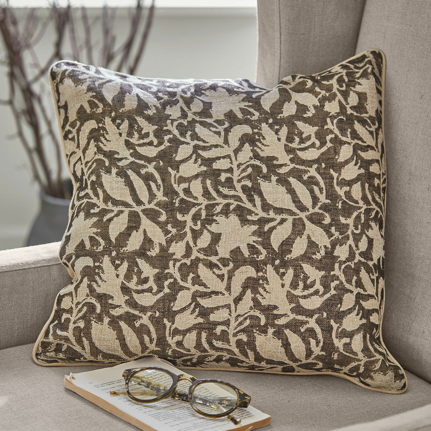 Kissenhülle 2er Set Ziradayn Braun-beige Baumwollkissen mit floralem Muster auf grauem Sofa mit Brille und Buch