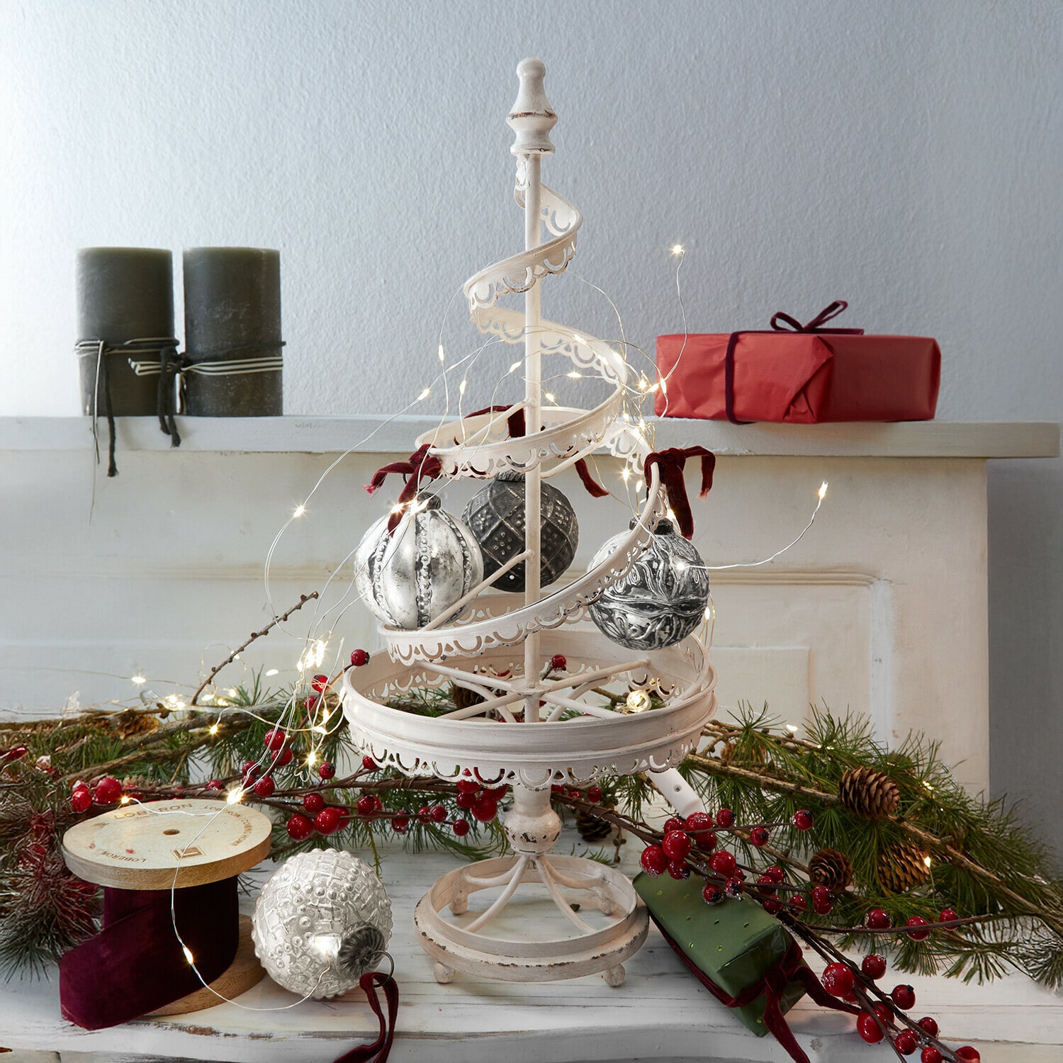Deko-Baum Gerzat Weiße Metall-Weihnachtsdekoration mit hängenden Kugeln und LED-Lichterkette, rote Geschenke und Tannenzweige im Hintergrund
