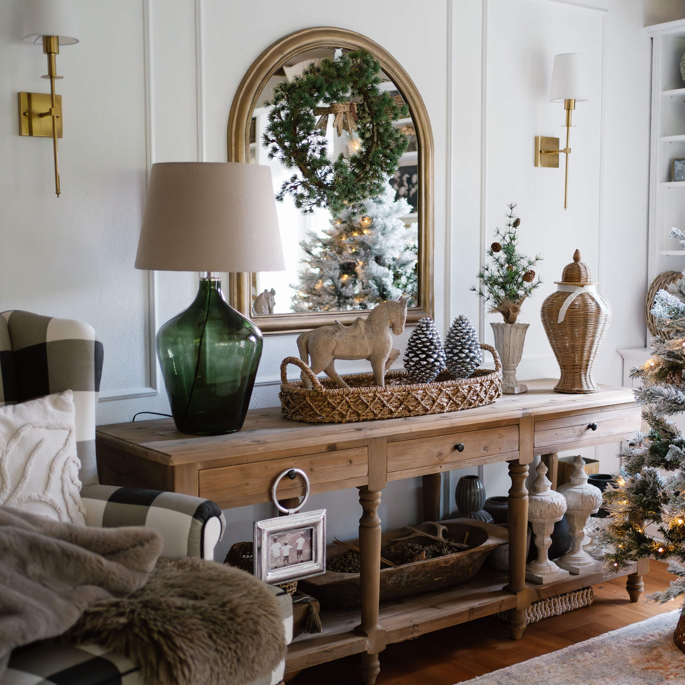 Holztisch mit Weihnachtsdekoration, grünem Lampenfuß und Spiegel mit Kranz in gemütlichem Wohnzimmer