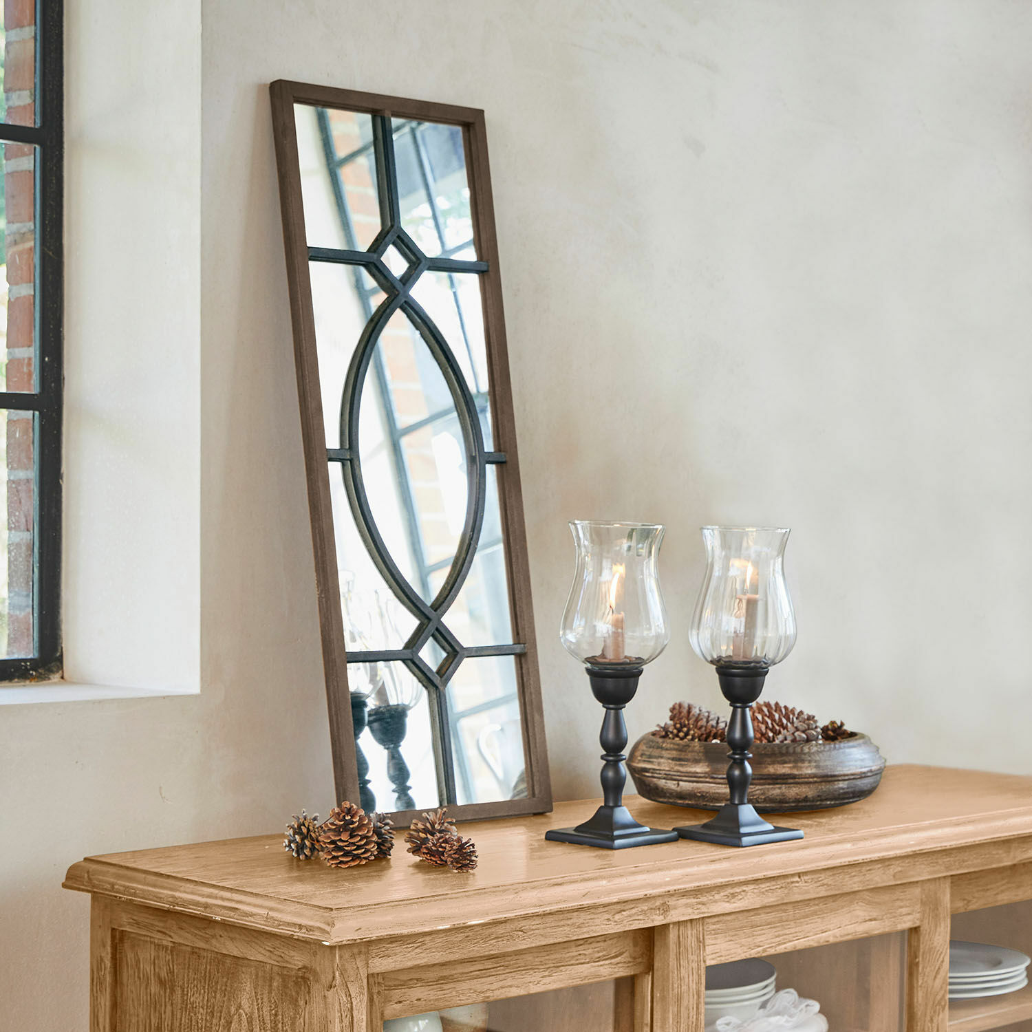 Holzkonsole mit gerahmtem Spiegel und zwei Glas-Metall-Kerzenhaltern als Wohnaccessoire
