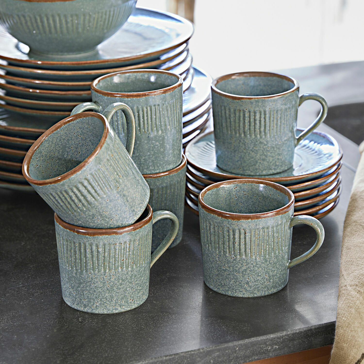 Tasse mit Untertasse 6er Set Périers Set aus grünen Keramiktassen und Tellern mit braunem Rand auf Küchenarbeitsplatte