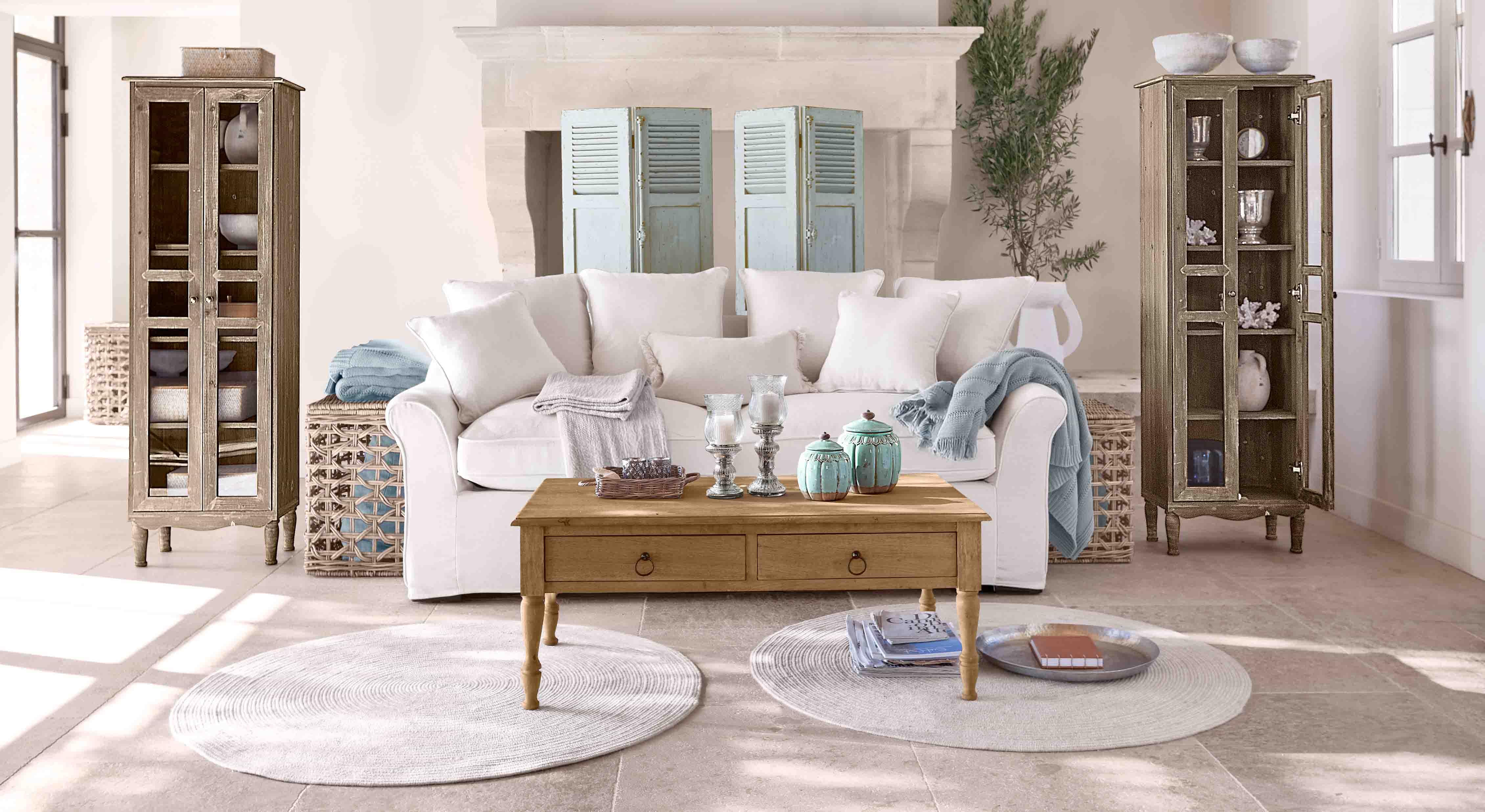 Gemütliches Wohnzimmer mit weißem Sofa, Holzcouchtisch und zwei antiken Holzvitrinen
