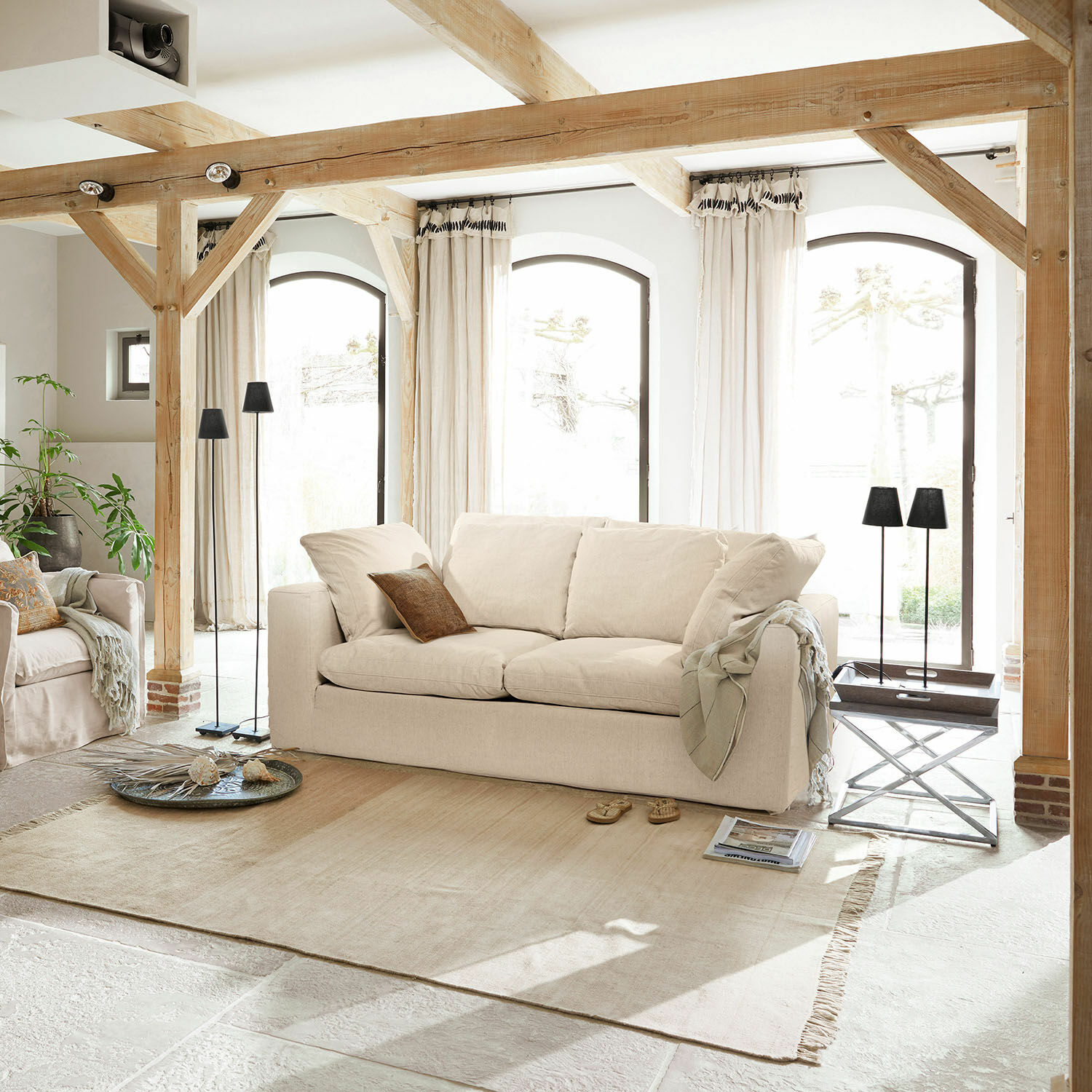 Sofa Xavreille Beige Stoffsofa in hellem Wohnzimmer mit Holzbalken und großen Fenstern