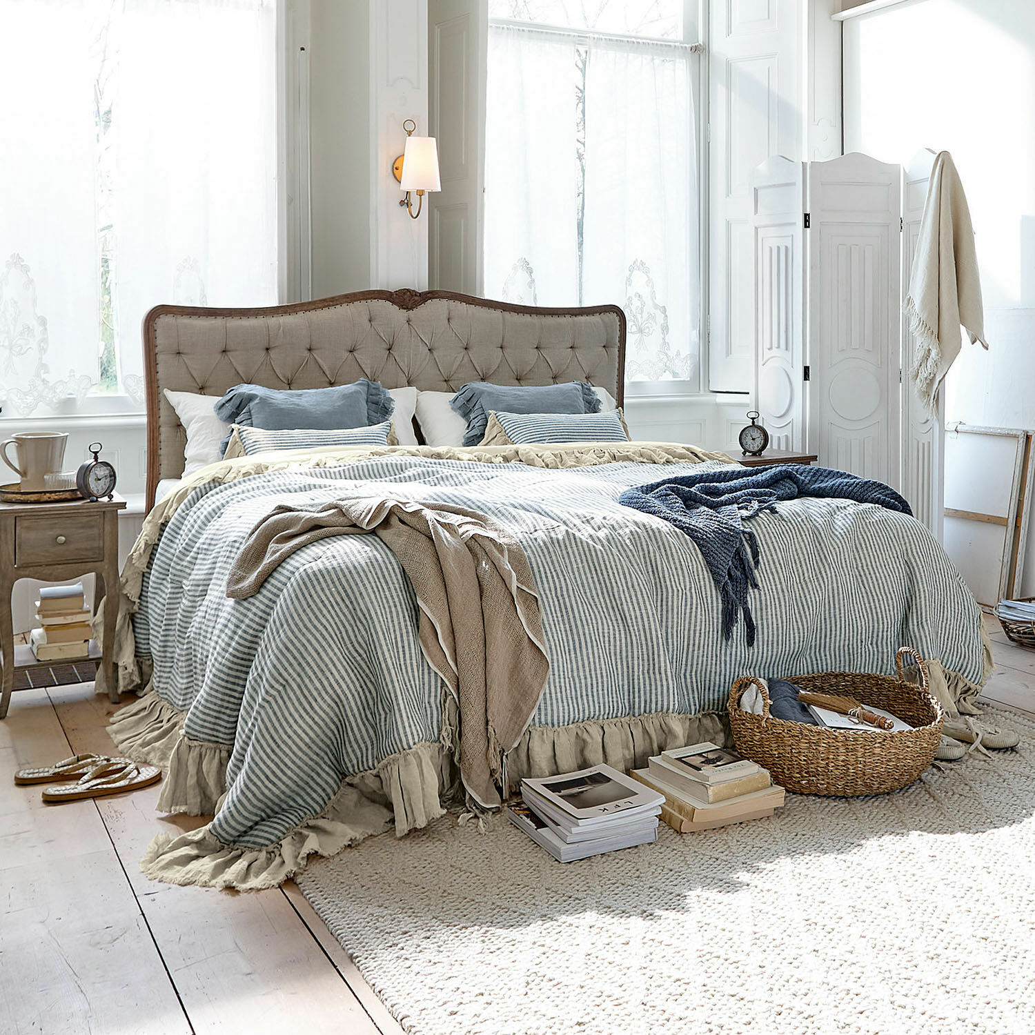 Quilt Alexane Gemütliches Schlafzimmer mit beige gepolstertem Bett und blau-weiß gestreifter Bettwäsche