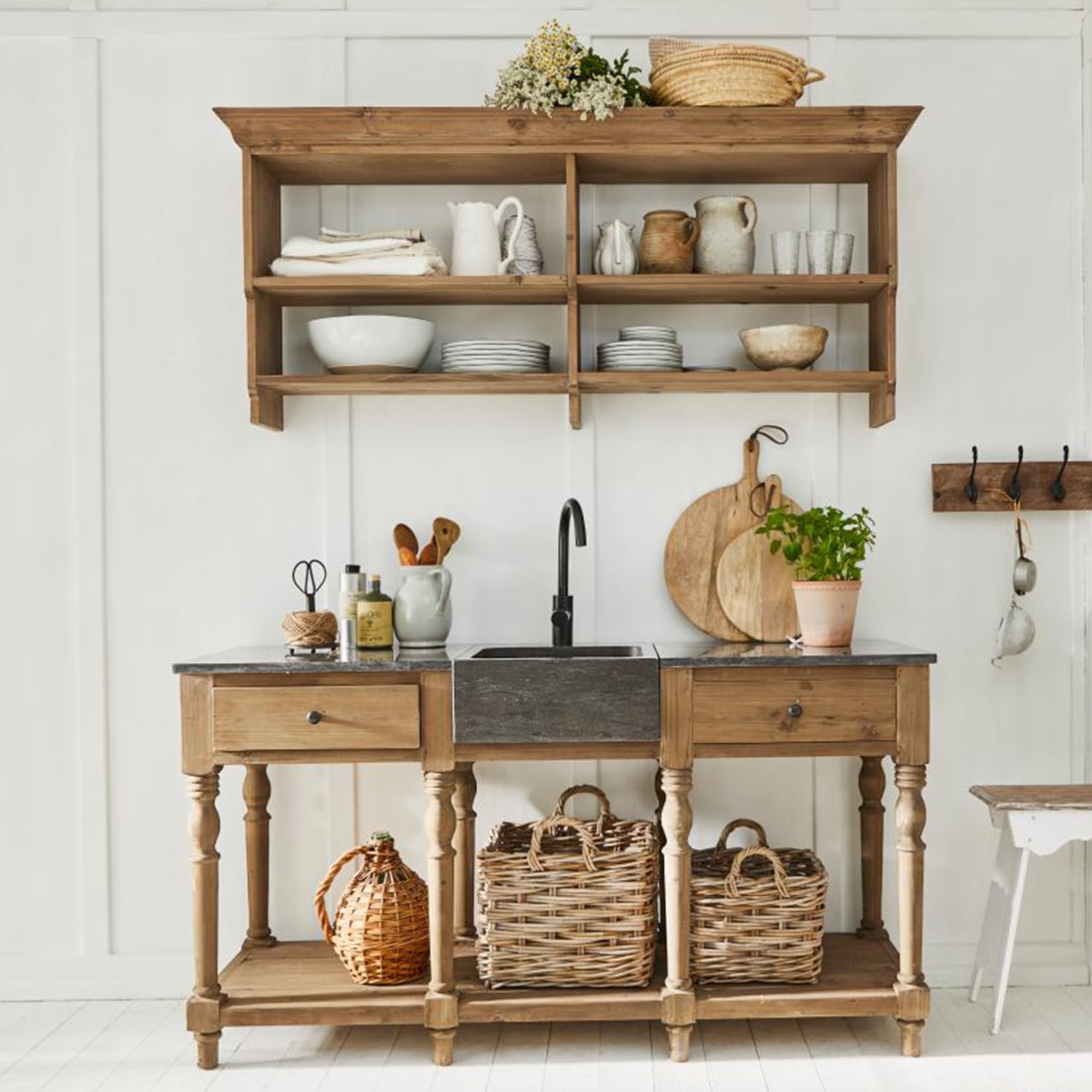 Rustikale Holzküche mit schwarzem Spülbecken und Korbgeflecht vor weißer Wand