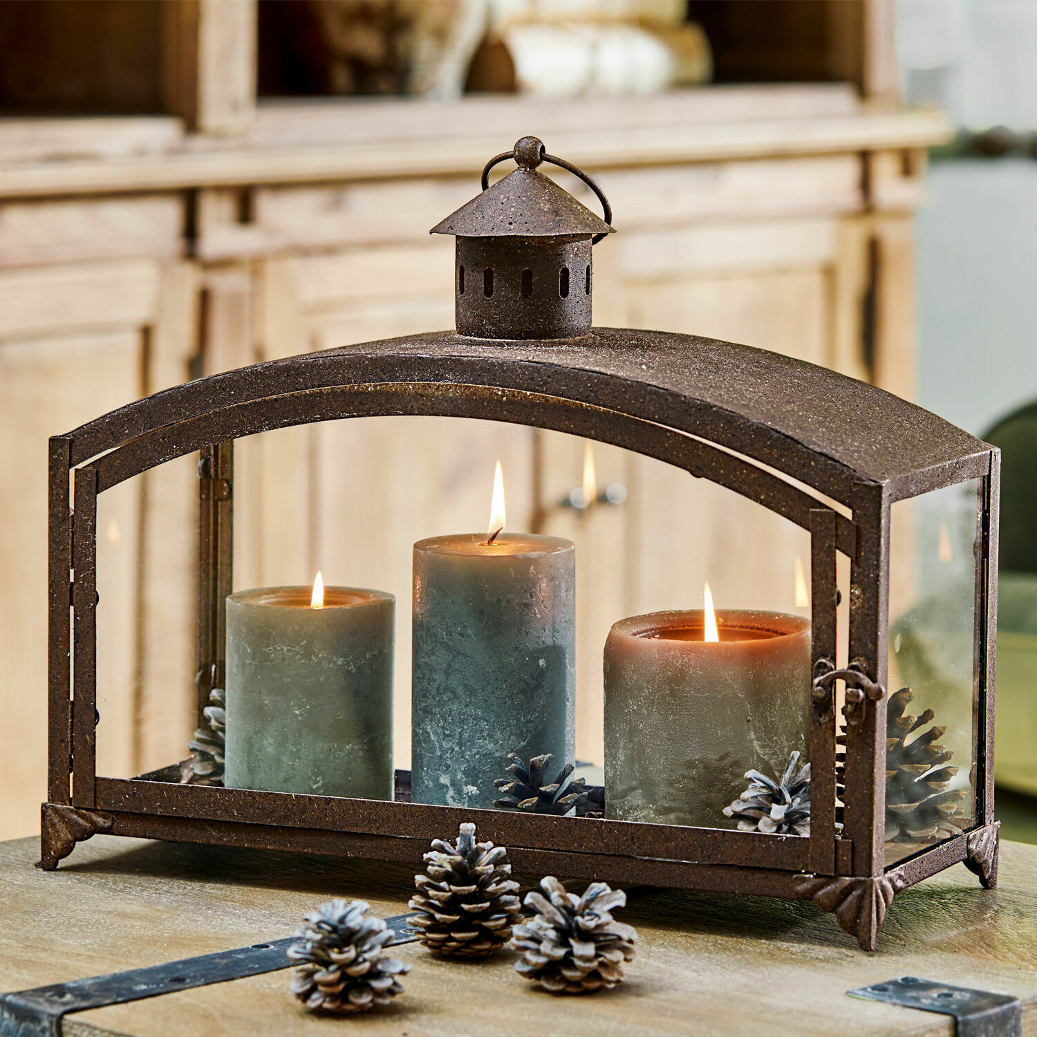 Laterne Miora Metall-Laterne mit drei grünen Kerzen und Kiefernzapfen auf Holztisch, Wohnraumdekoration