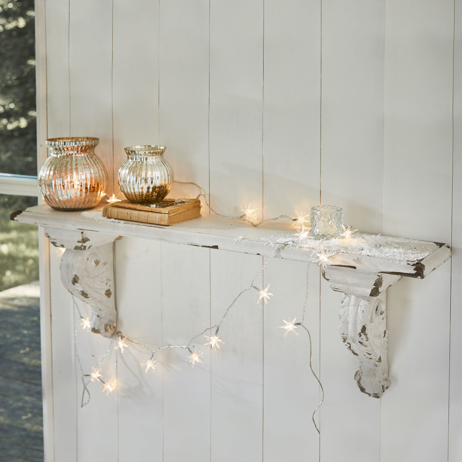 Wandregal Mouscron Weiße Holz-Wandkonsole mit Shabby-Chic-Effekt, dekoriert mit Stern-Lichterkette und Glaswindlichtern