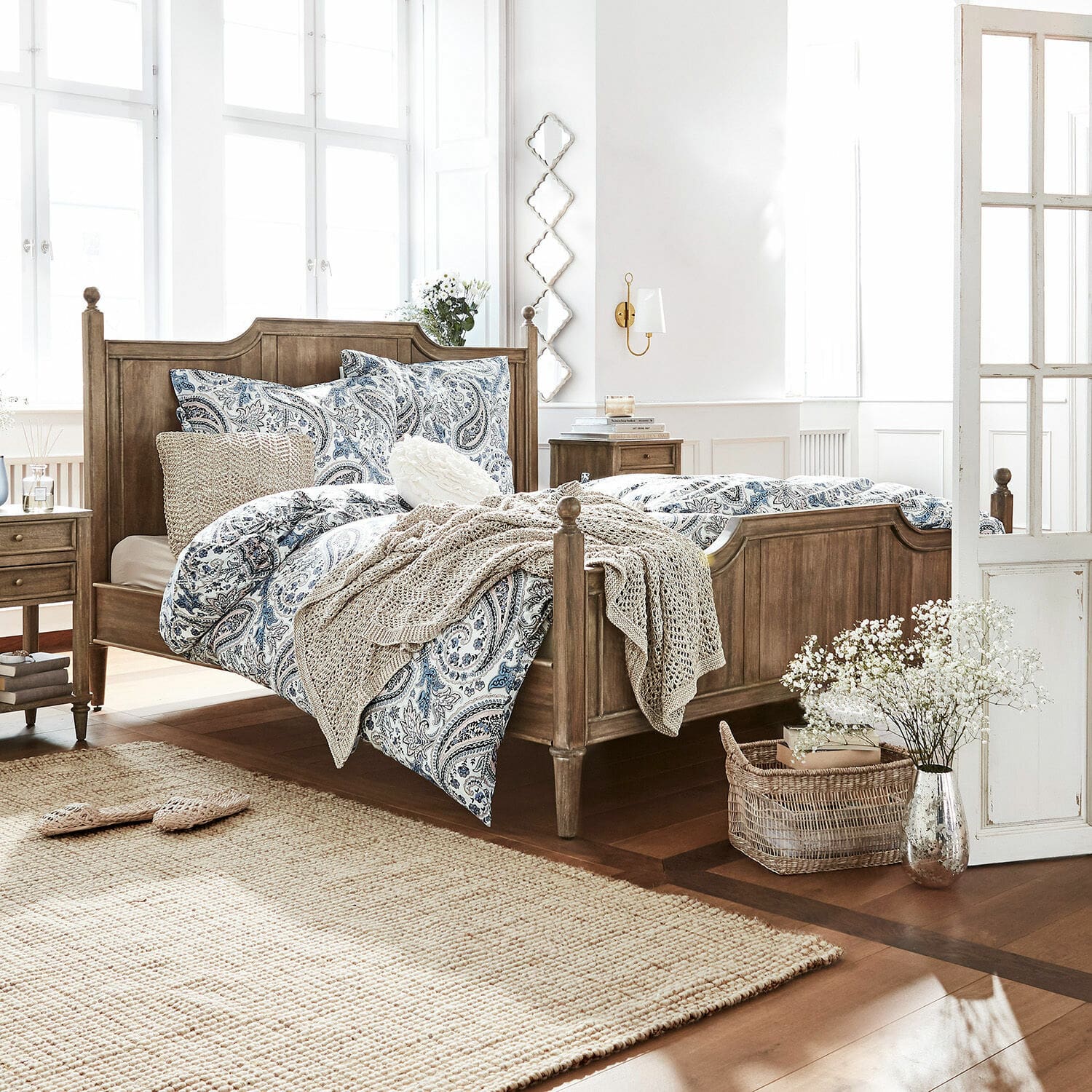 Bett Lubbock Schlafzimmer mit Holzbett und blau-weißem Paisley-Bettwäsche, Naturteppich und Dekorationen