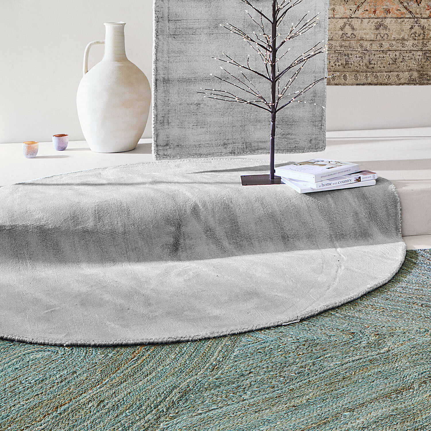 Runder grauer Teppich aus weichem Material mit Innendekoration aus Büchern und Vase