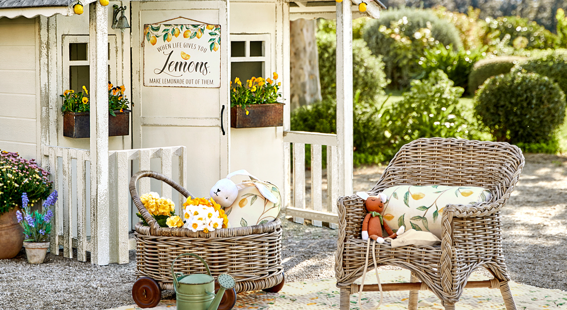 Kleiner Garten mit Rattansessel und Rollkorb mit Kissen und Spielzeug, Gartendekoration
