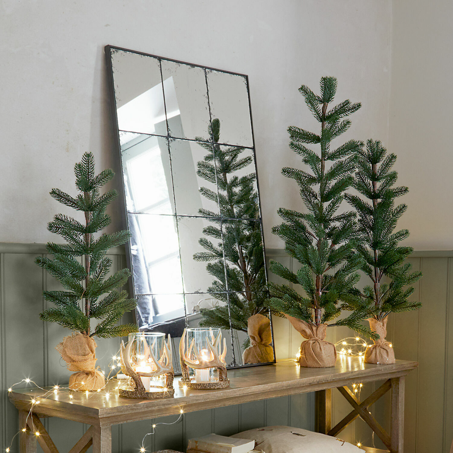 Deko-Baum 3er Set Merpins Dekorative künstliche Tannenbäume in Jutesäcken auf Holztisch mit LED-Lichterkette und Spiegel