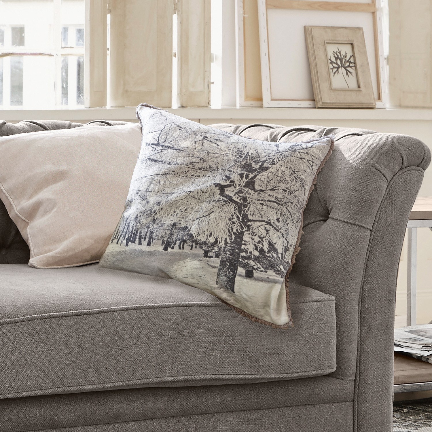Kissen Forrest Graues Sofa mit zwei Kissen, eines mit Winterbaum-Motiv, gemütliche Wohnzimmerdekoration