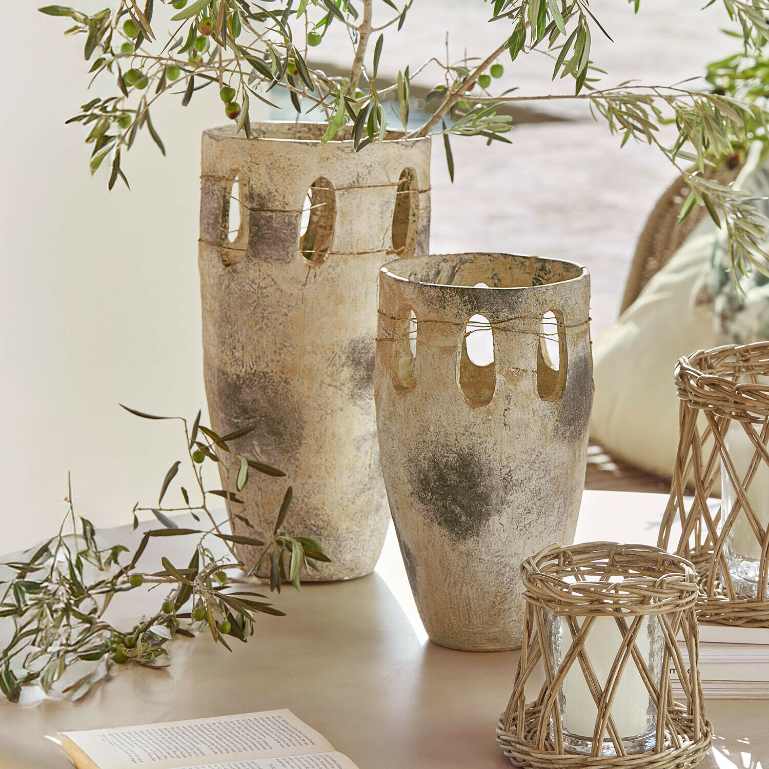 Vase 2er Set Delunas Zwei dekorative Vasen aus Stein in Beige-Grau mit Öffnungen und Olivenzweigen auf einem Tisch
