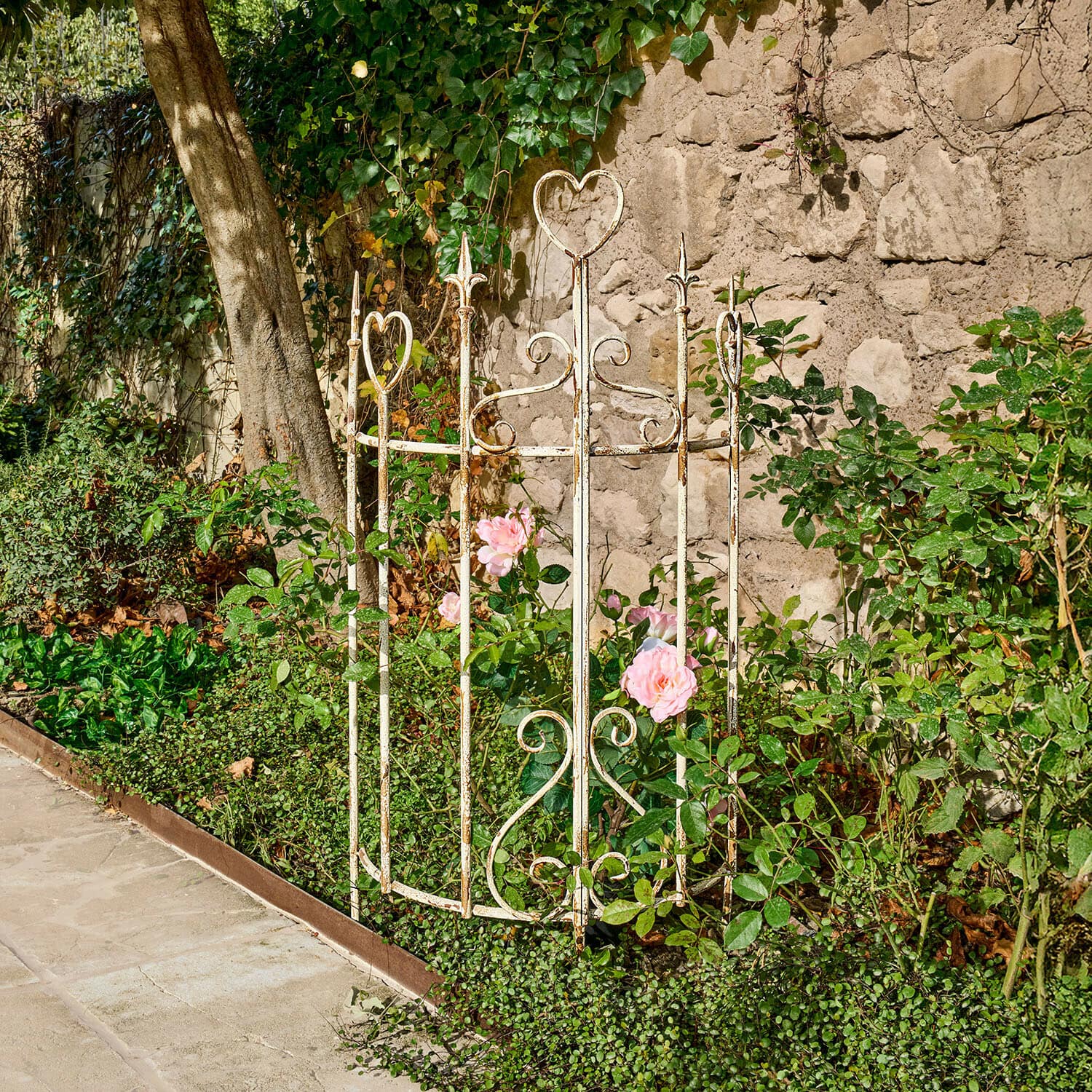 Weiße Metallpflanzenschutz mit Herzmotiven im Garten für Rosen und Blumen