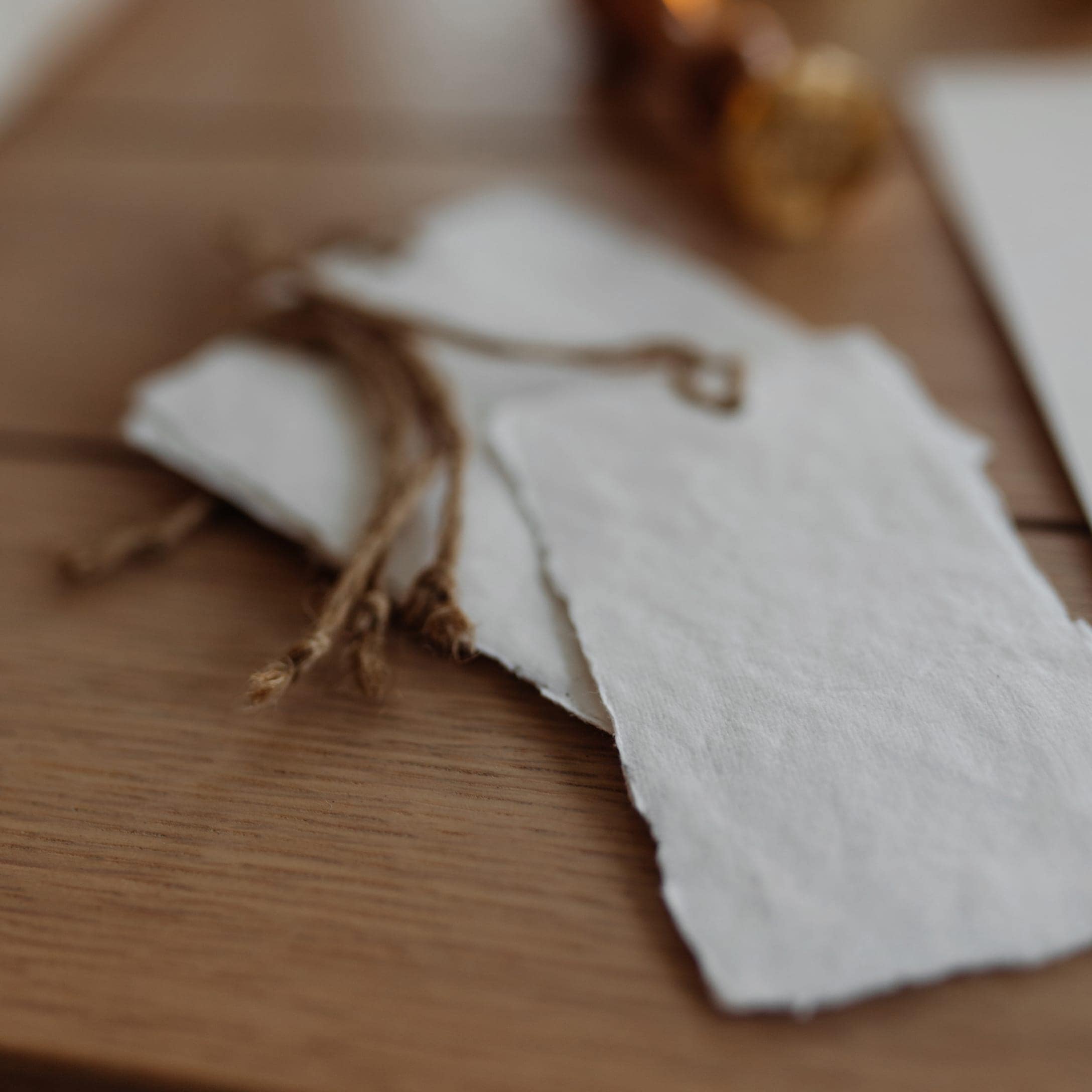 Weiße Papieranhänger mit Naturkordel zum Geschenkverpacken auf Holztisch