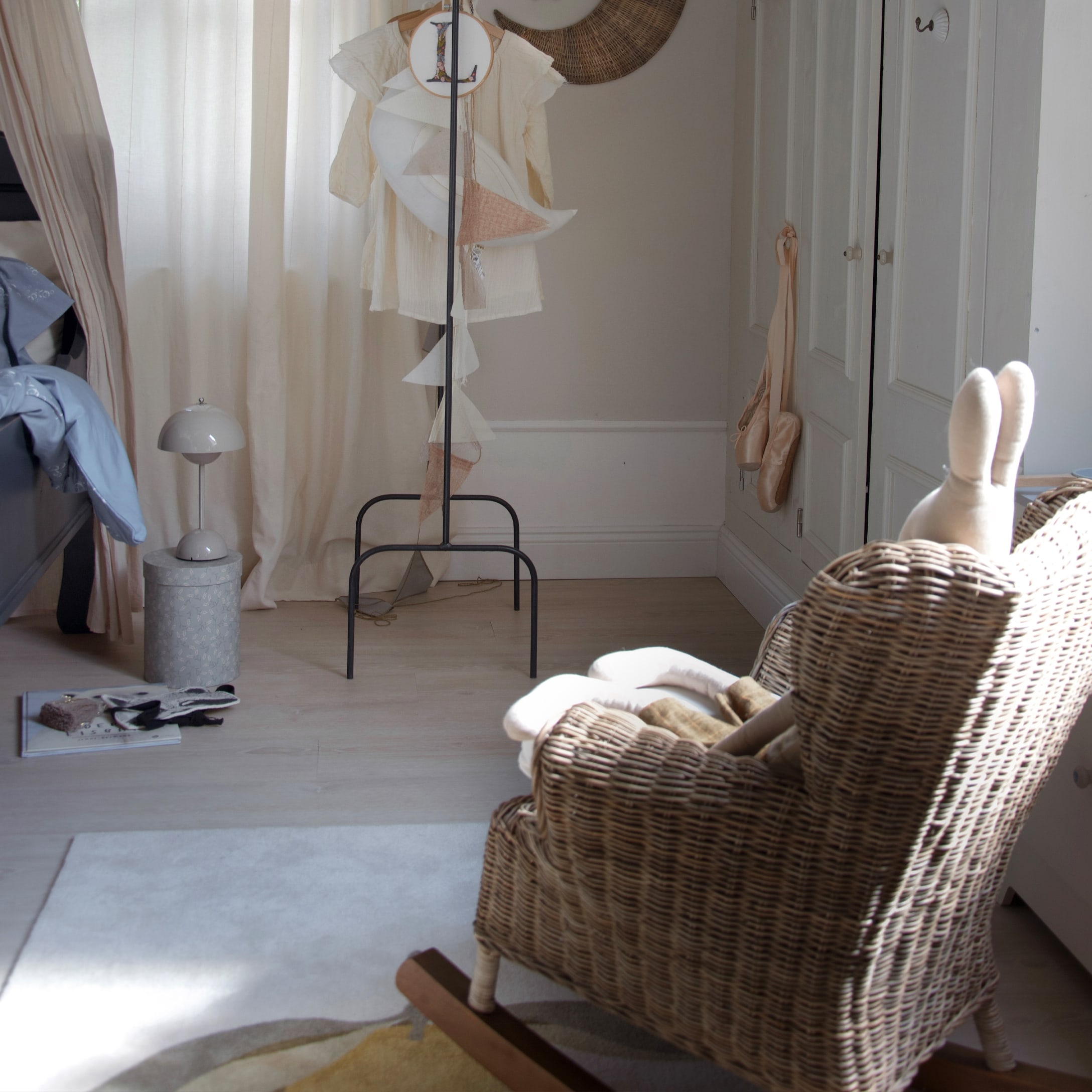 Gemütliches Kinderzimmer mit Rattansessel und hellen Vorhängen, natürliche Materialien im Raum