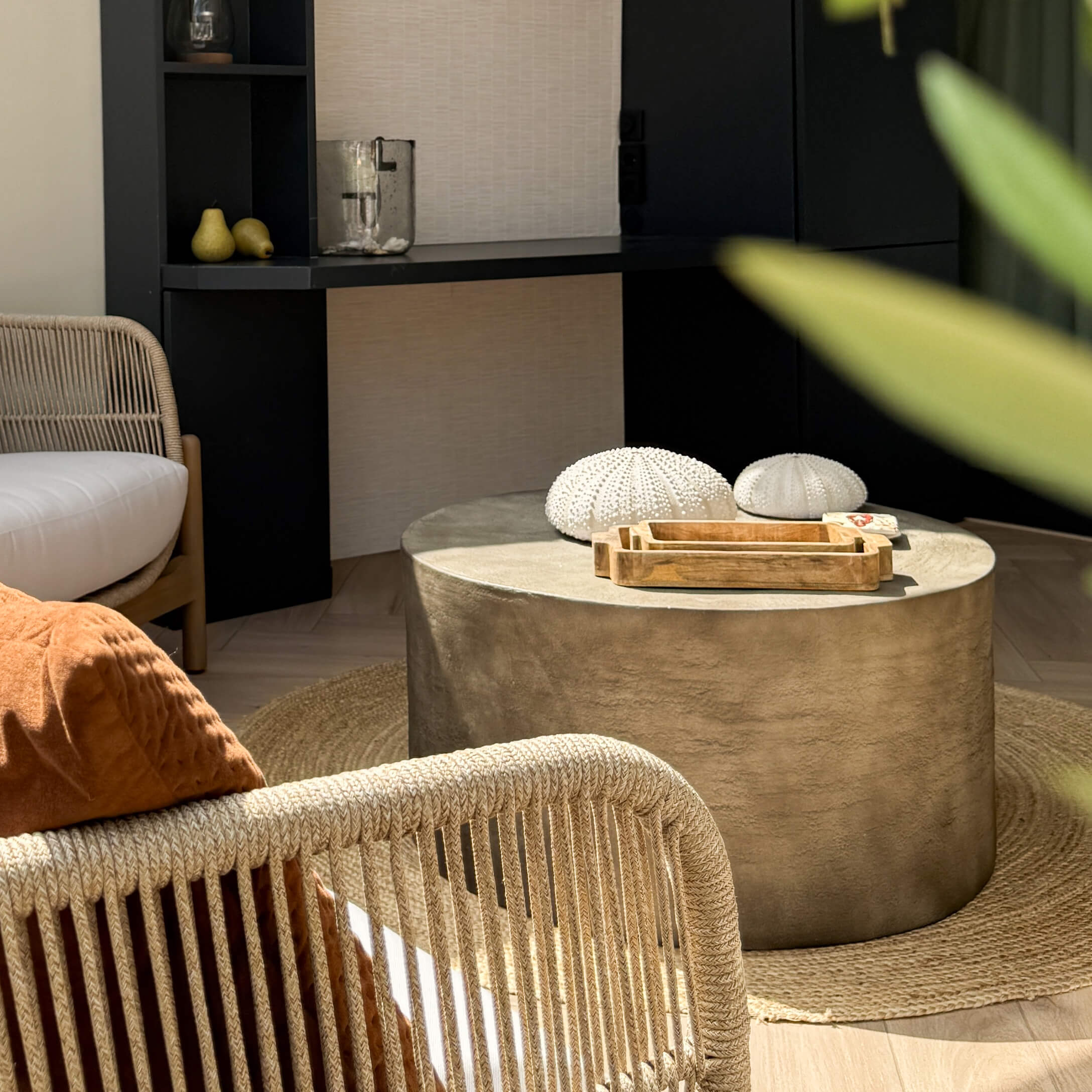 Runder Couchtisch aus beigem Beton auf rundem Naturfaserteppich in modernem Wohnzimmer