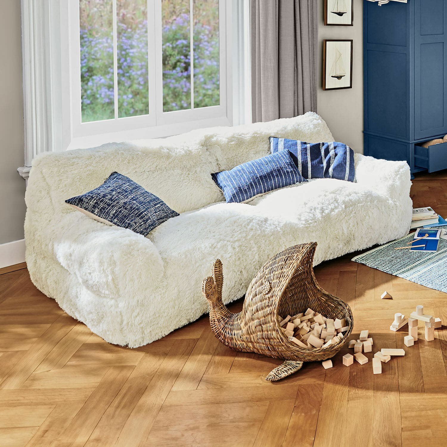 Kindersofa Cerveteri Weißes, flauschiges Sofa mit blauen Kissen in hellem Wohnzimmer mit Holzparkett