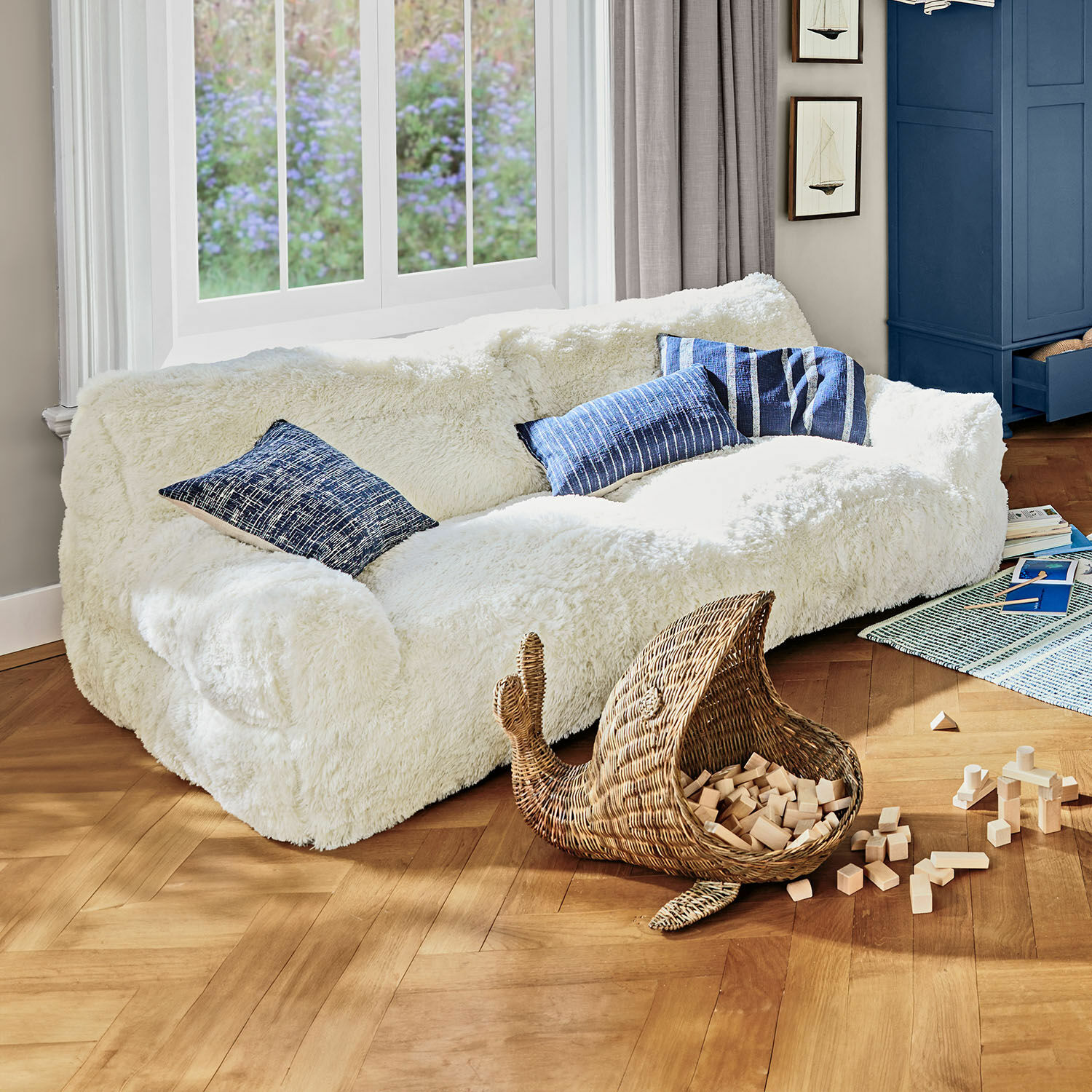 Kindersofa Cerveteri Weißes, flauschiges Sofa mit blauen Kissen in hellem Wohnzimmer mit Holzparkett