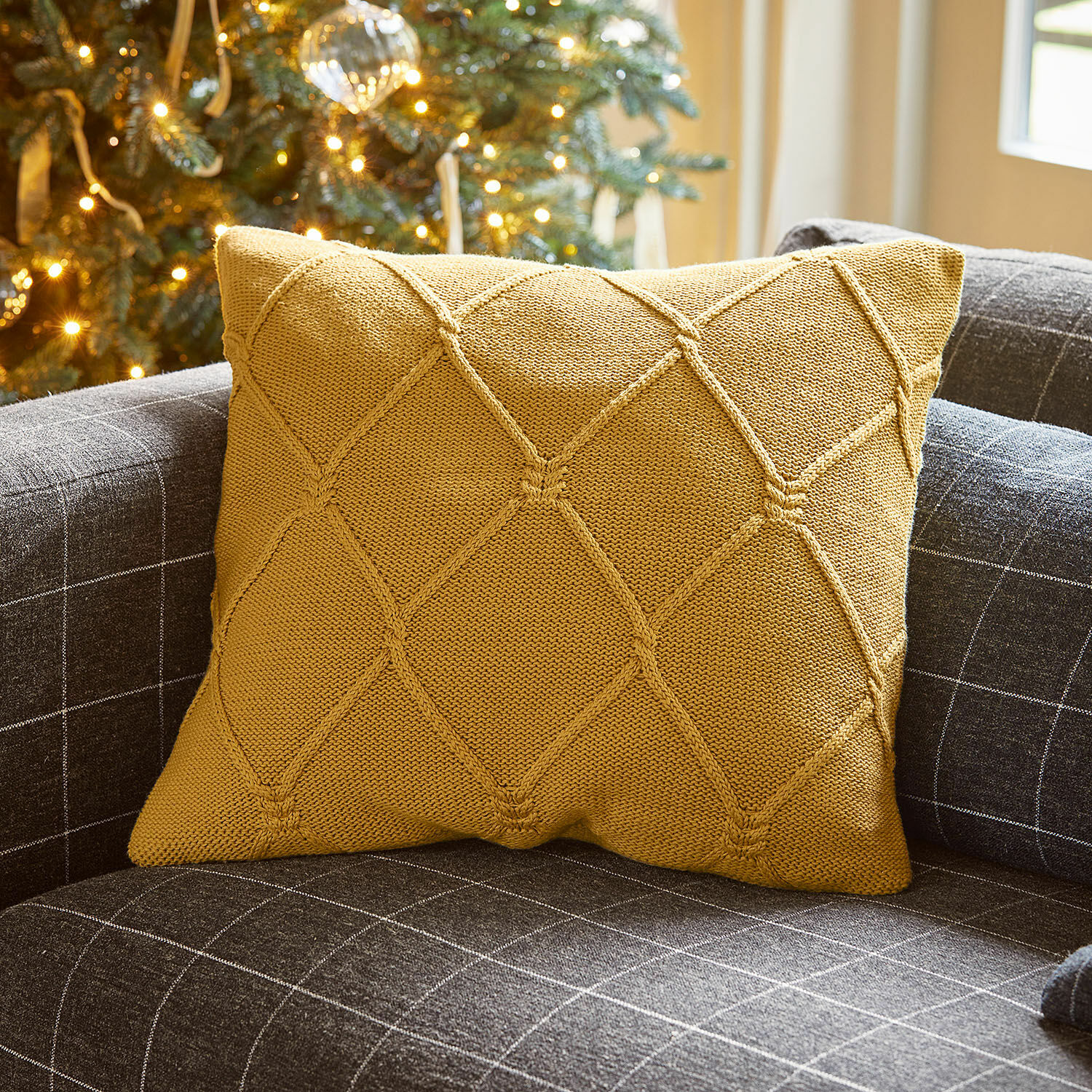 Kissenhülle Cresil Senfgelbe Strickkissen auf grauem Sofa mit Karomuster für gemütliches Wohnzimmer