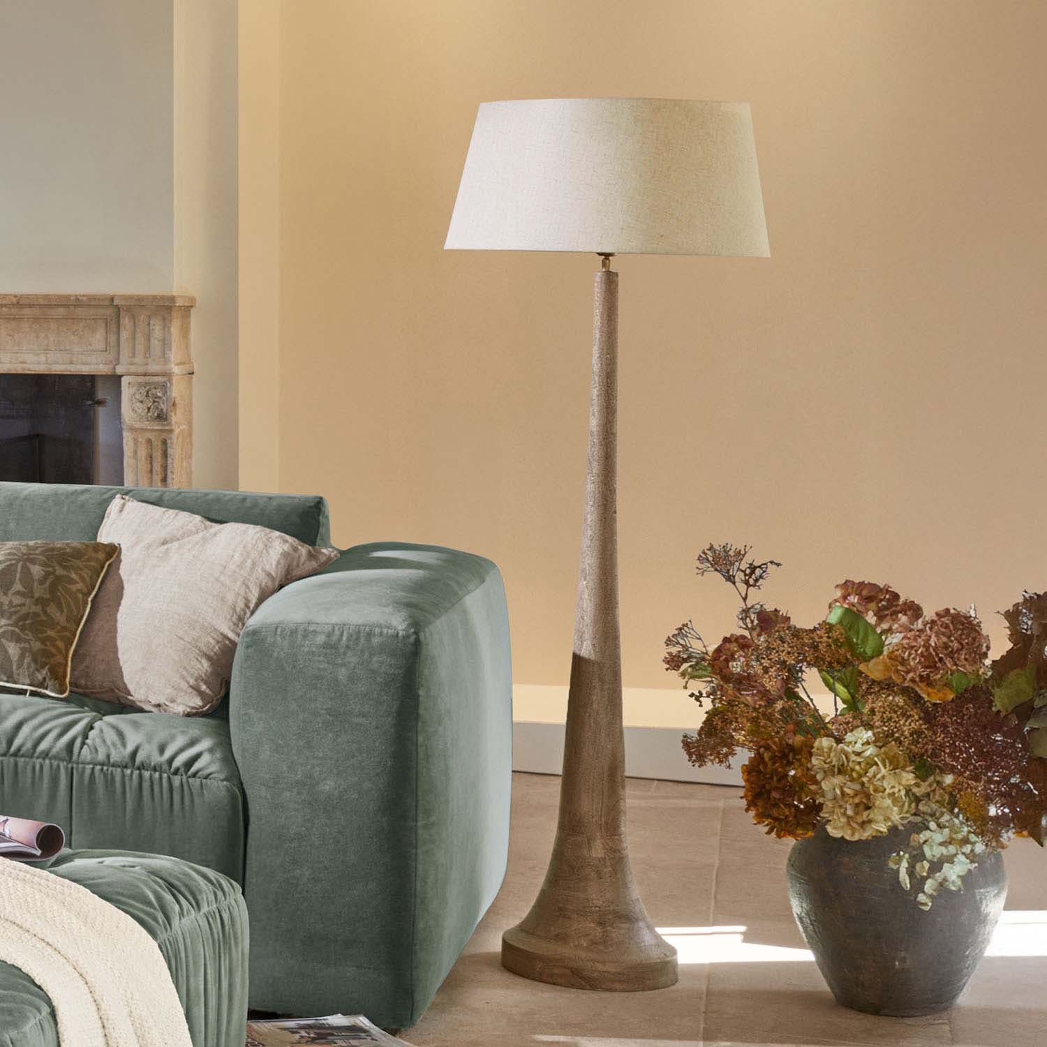Stehlampe mit Holzfuß und beigem Lampenschirm im modernen Wohnzimmer mit grünem Sofa