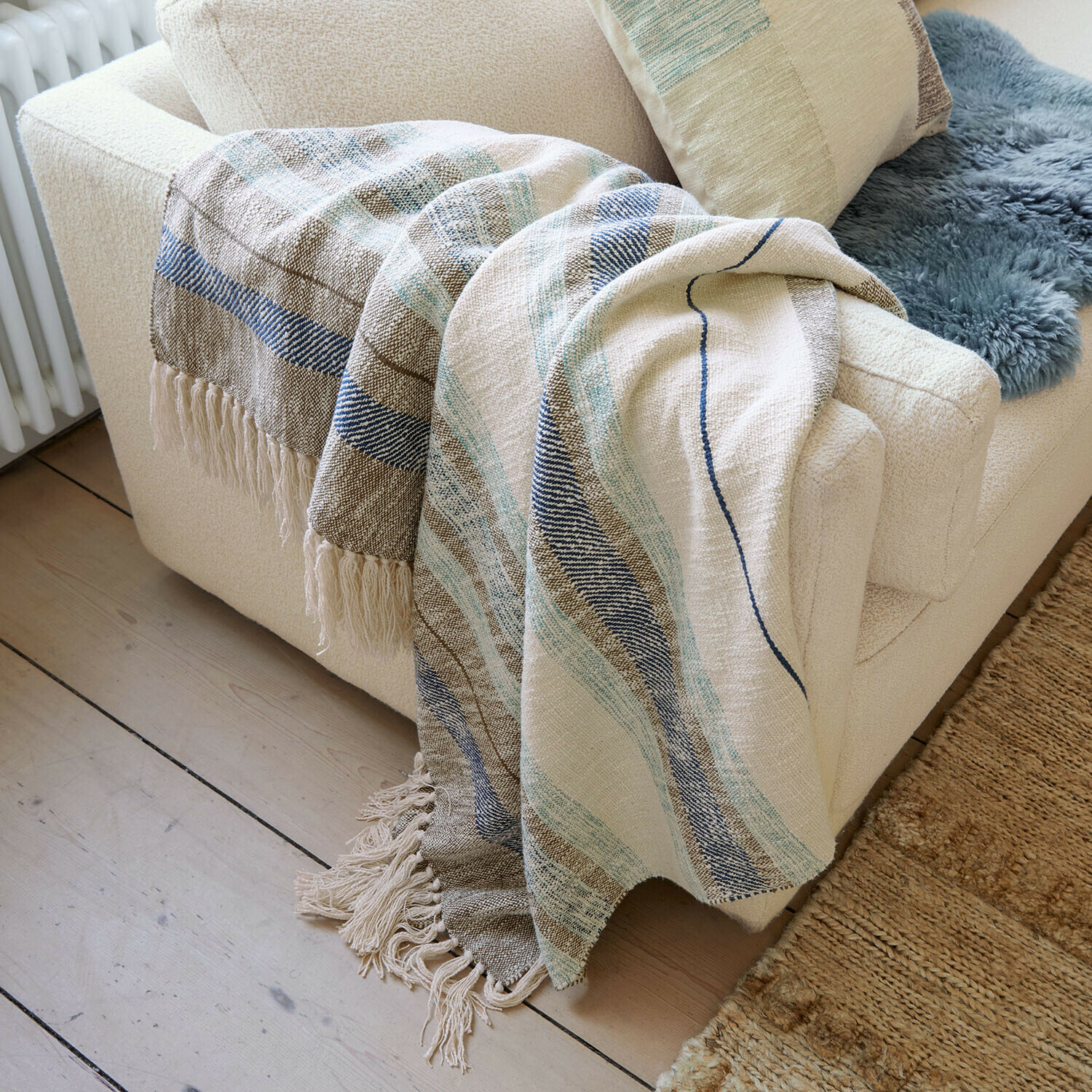 Plaid Maresas Weiche Baumwolldecke in Beige mit blauen Streifen und Fransen auf cremefarbenem Sofa im Wohnzimmer