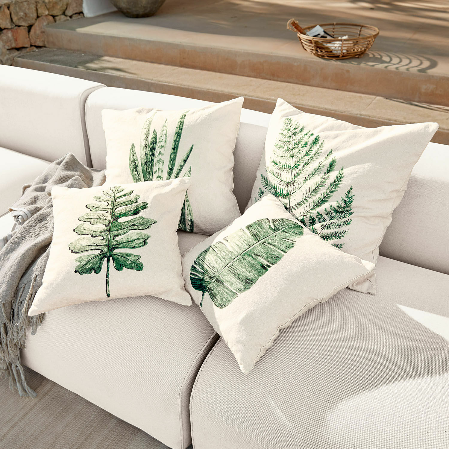 Kissenhülle 4er Set Marly Vier cremefarbene Kissen mit grünen Blattmotiven auf hellem Sofa, Wohnaccessoire