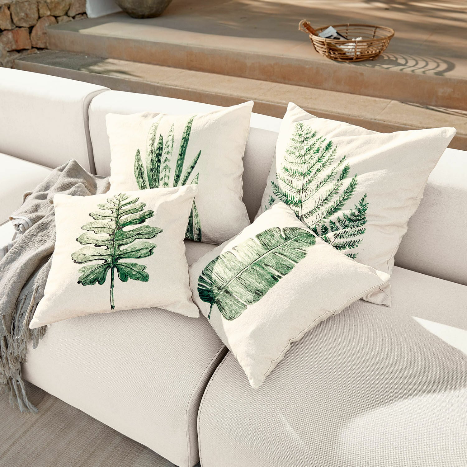 Kissenhülle 4er Set Marly Vier cremefarbene Kissen mit grünen Blattmotiven auf hellem Sofa, Wohnaccessoire