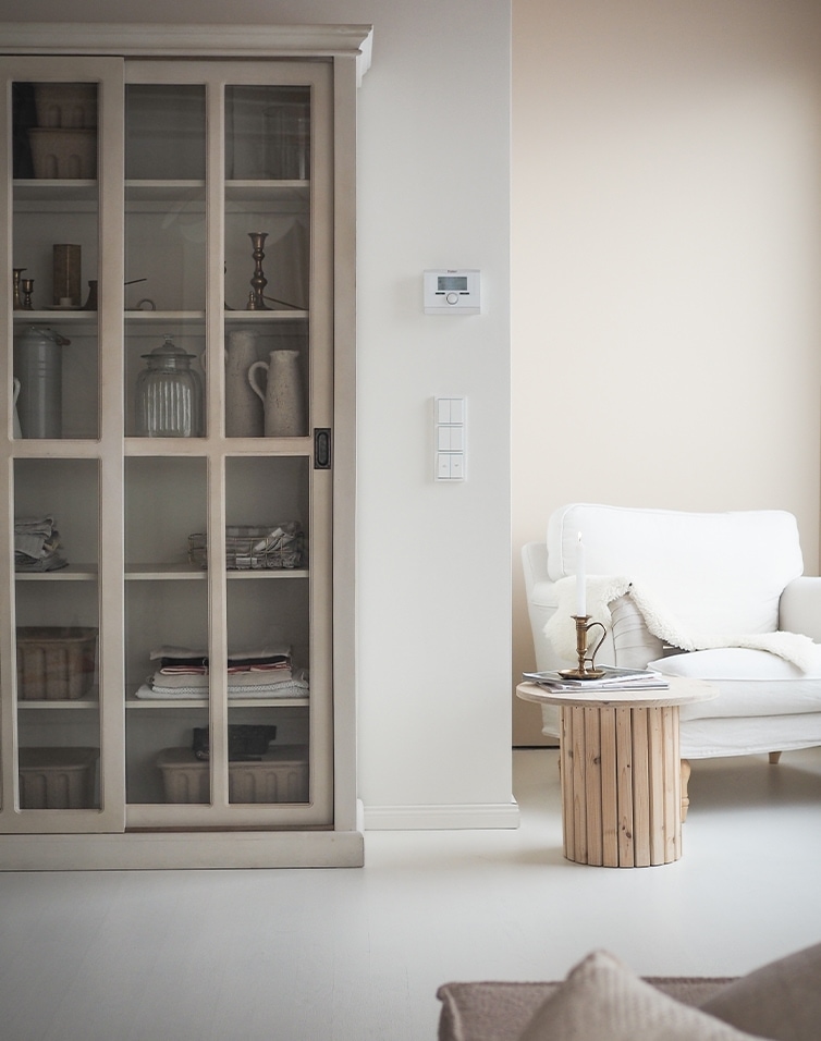Helles Wohnzimmer mit weißem Sofa, Holztisch und Vitrinenschrank im skandinavischen Stil