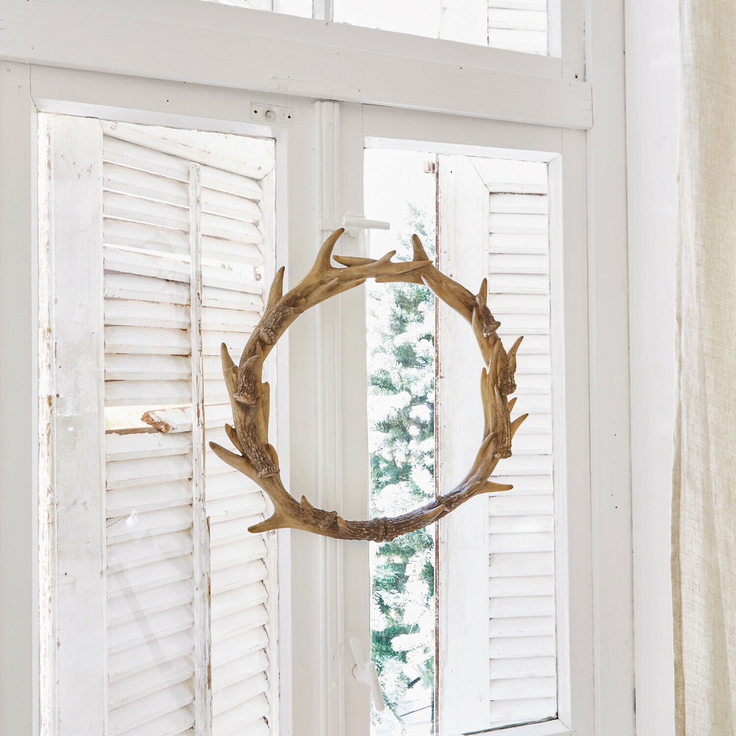 Kranz Marcelle Dekorativer Holzkranz in Geweihform am weißen Fenster mit Kerzen und Tannenzapfen