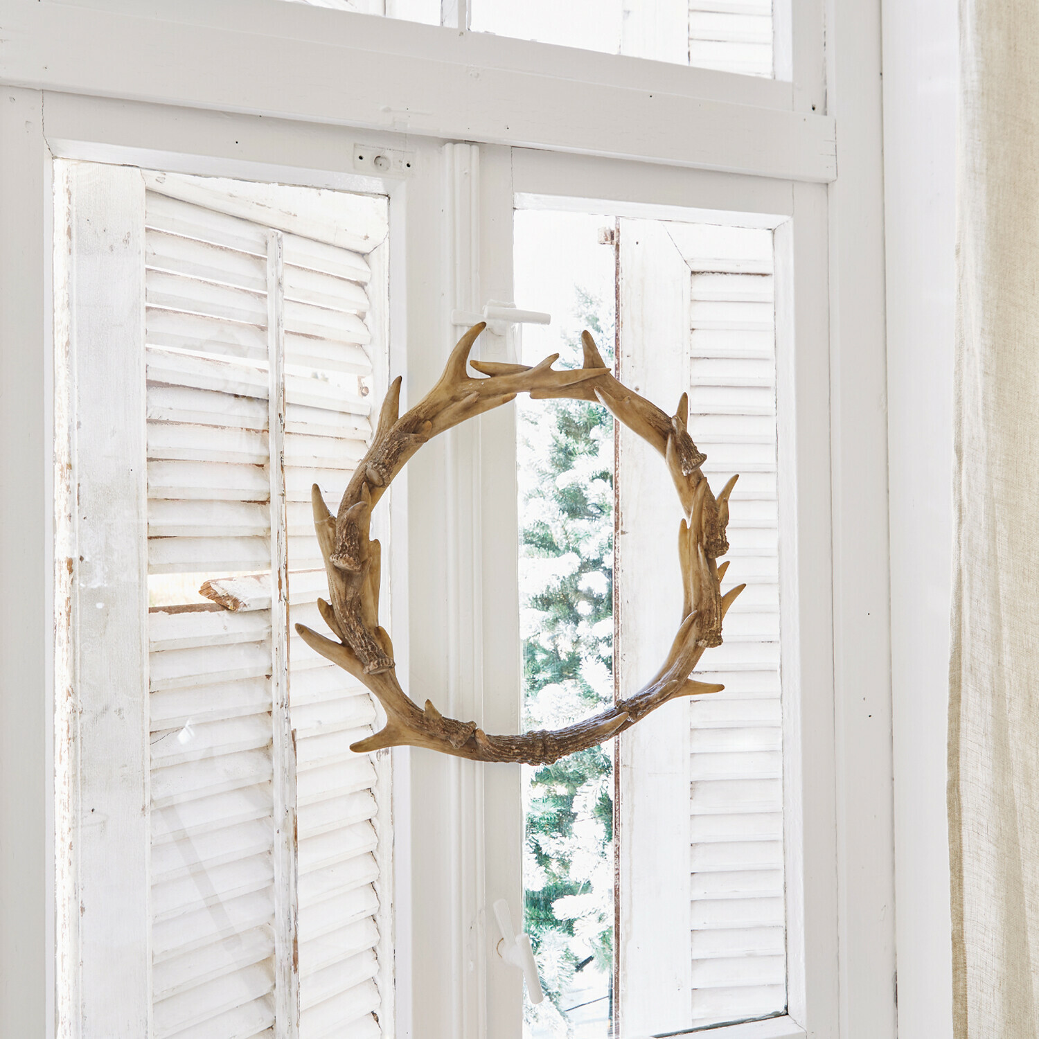 Kranz Marcelle Dekorativer Holzkranz in Geweihform am weißen Fenster mit Kerzen und Tannenzapfen