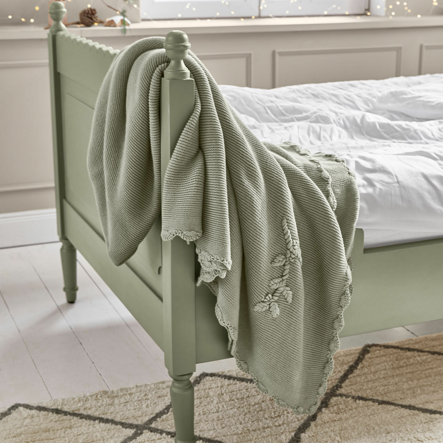 Mintgrüne Baumwolldecke mit Stickerei auf grünem Holzbett in hellem Schlafzimmer, Wohnaccessoire