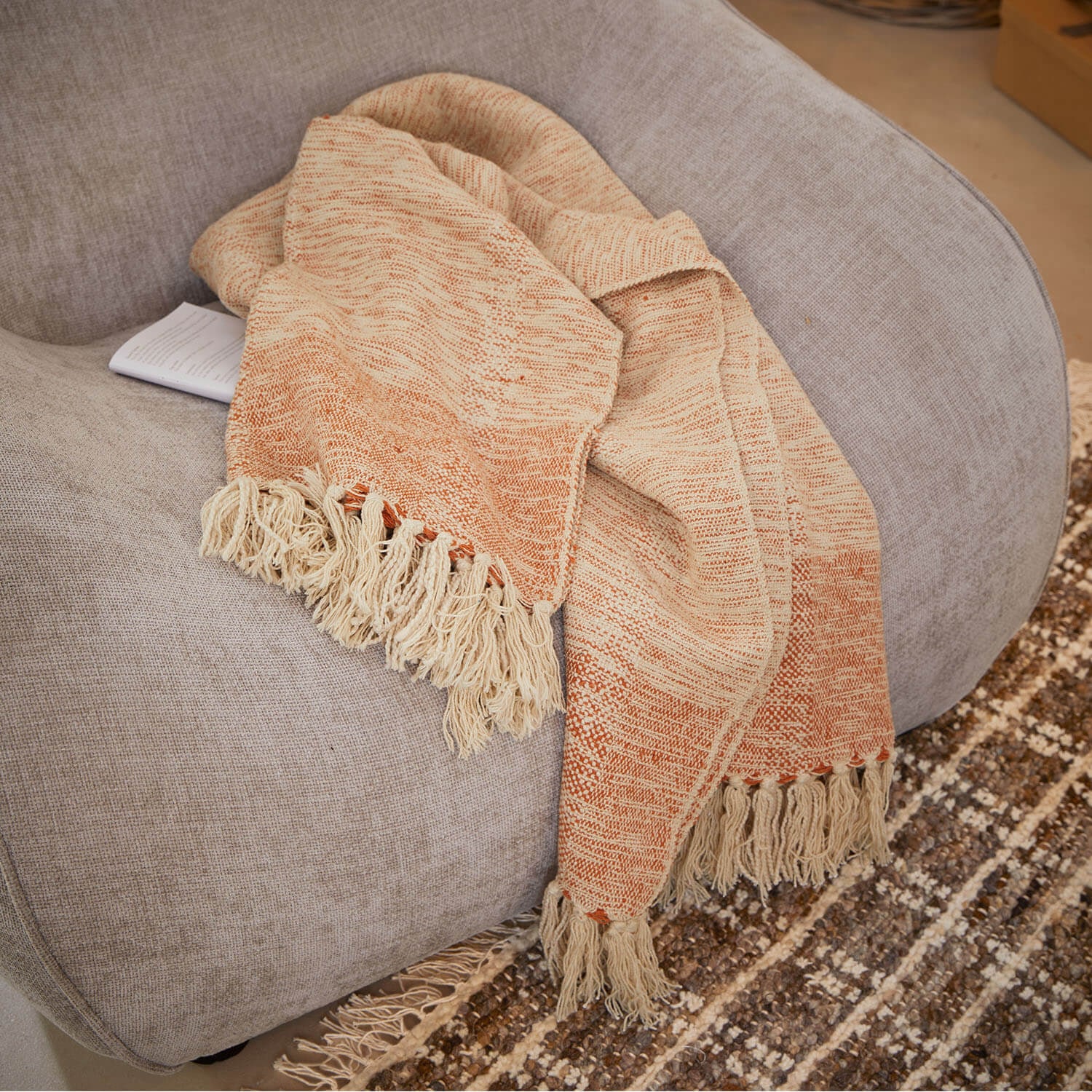 Beige-orangefarbene Decke mit Fransen auf grauem Sofa, weiches Material für Wohnraumdekoration