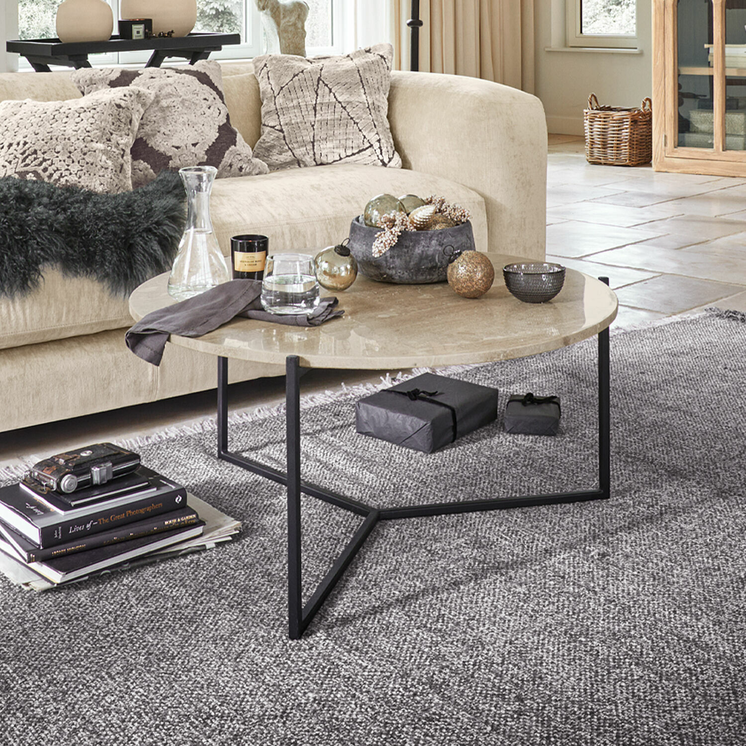 Couchtisch Émorieux Runder Couchtisch mit beigem Marmortischplatte und schwarzem Metallgestell auf grauem Teppich