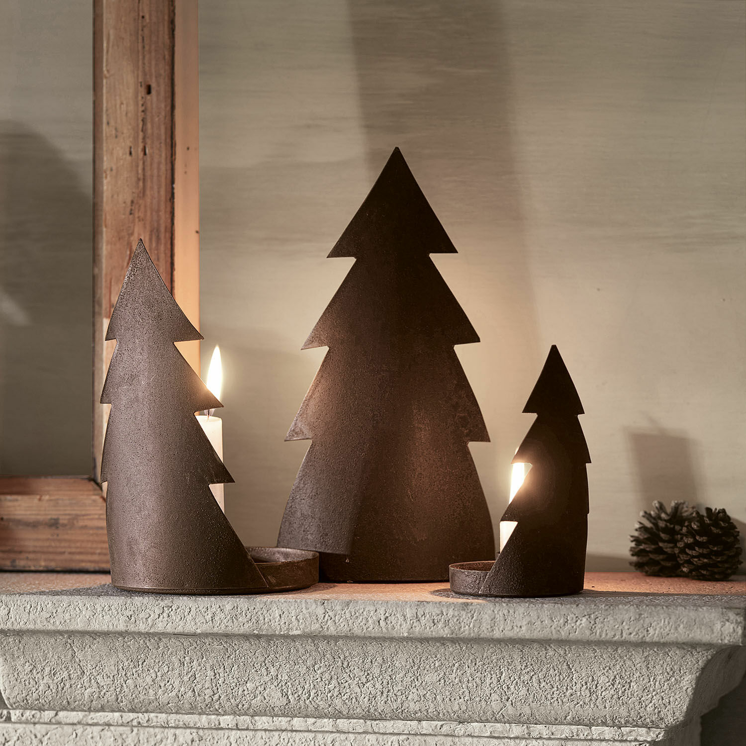 Kerzenständer 3er Set Ageville Drei rostfarbene Metall-Kerzenhalter in Tannenbaumform auf Kaminsims, weihnachtliche Dekoration