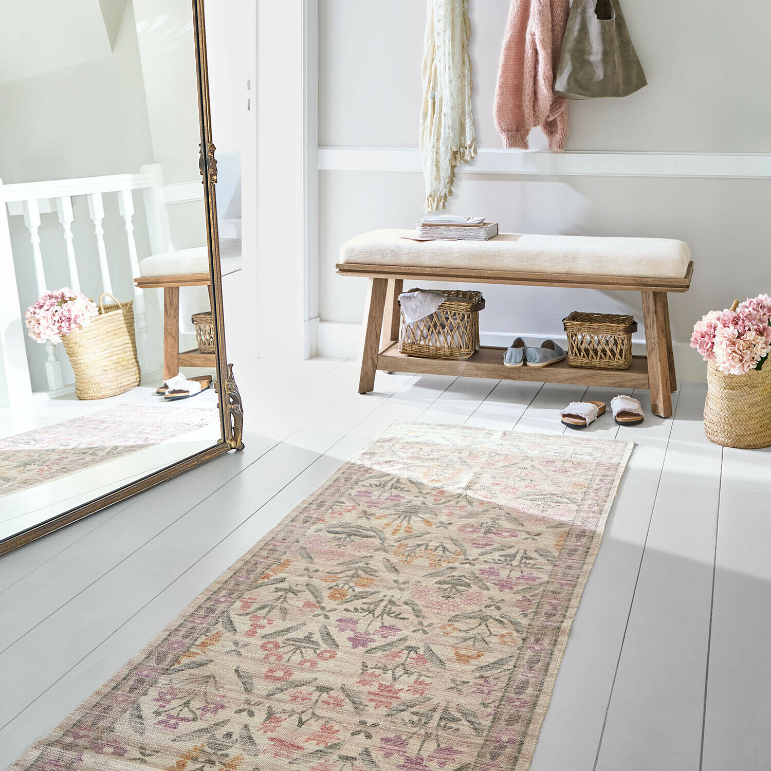 Helle Holzbank mit cremefarbenem Polster in hellem Raum mit floral gemustertem Teppich