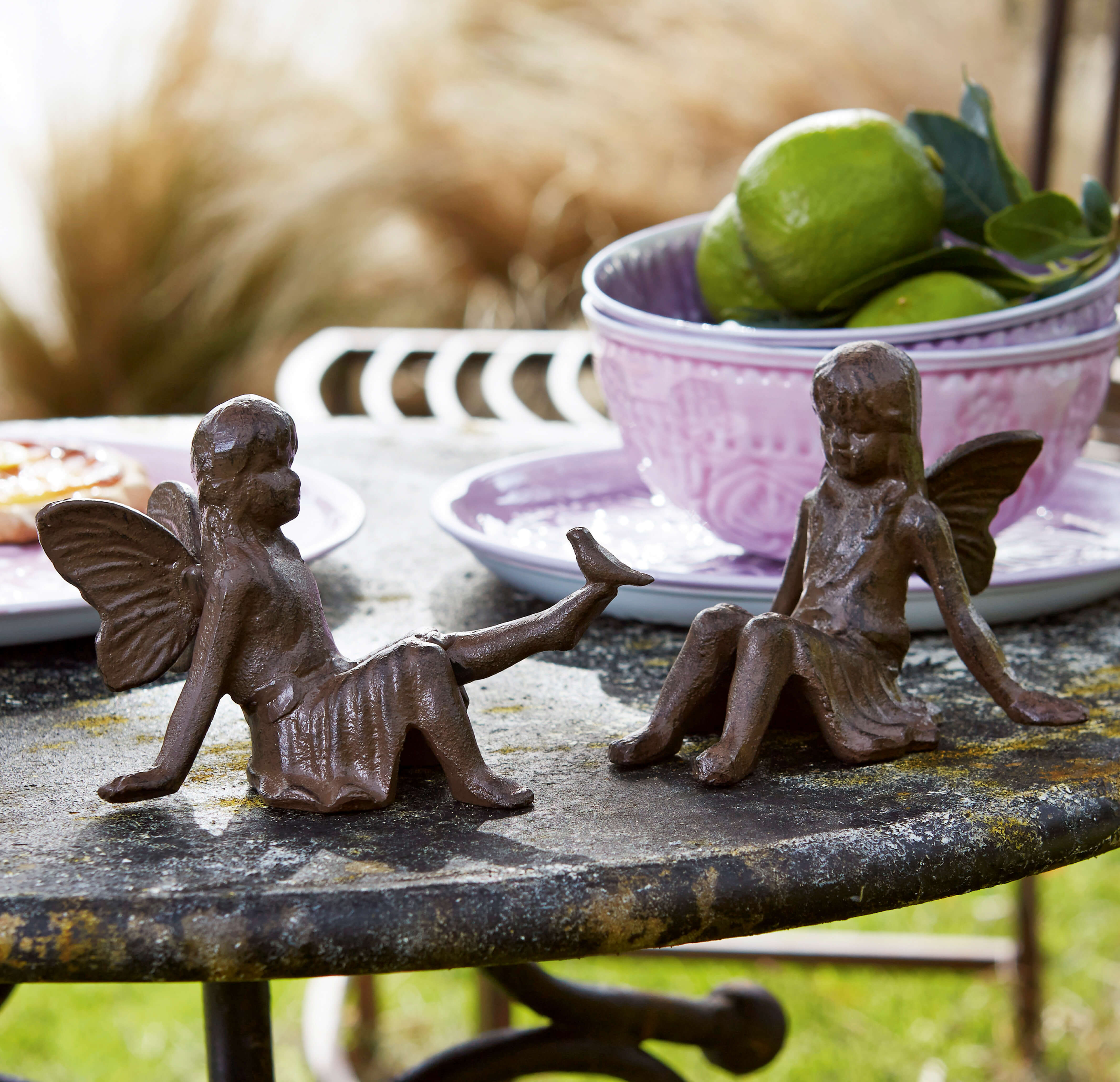 Zwei braune Gusseisen-Feenfiguren auf einem Steintisch im Garten, Gartendekoration