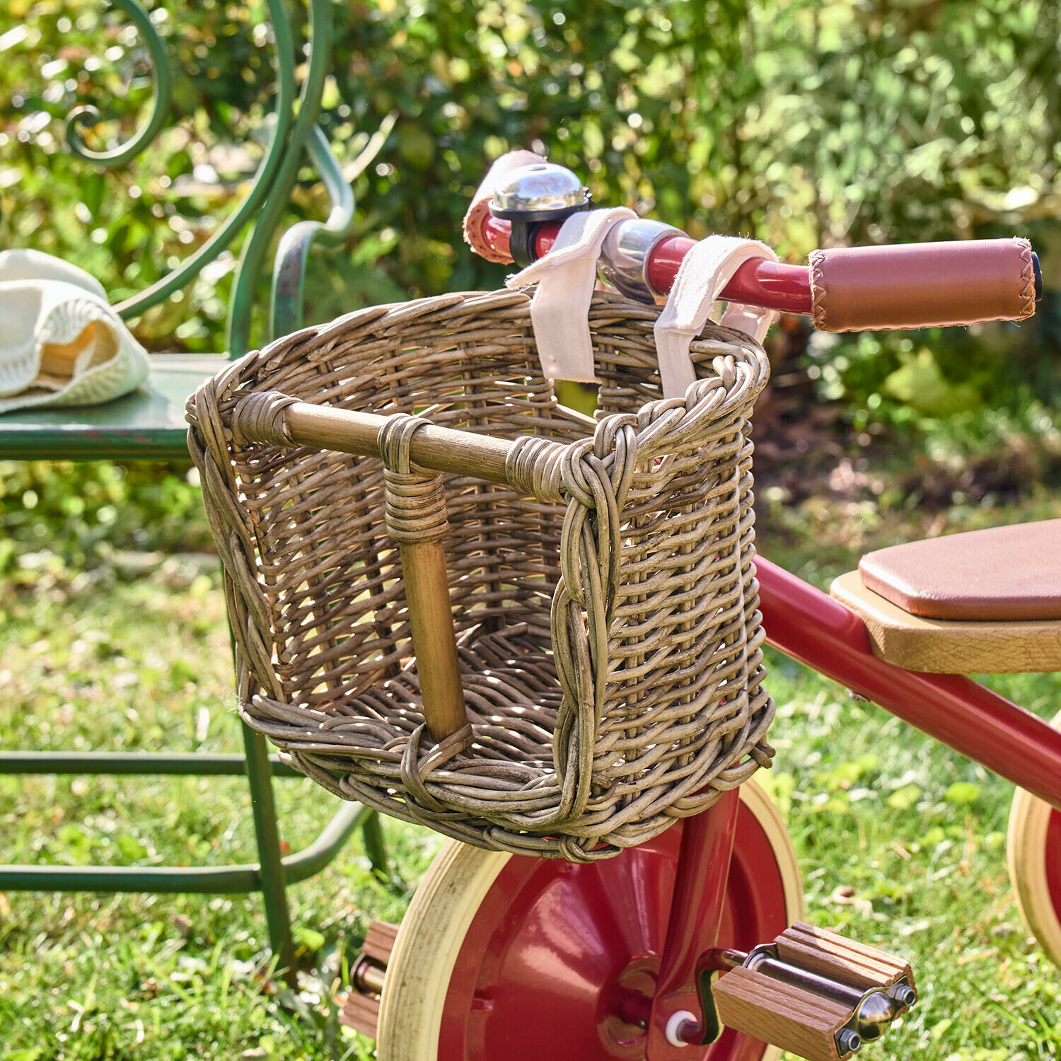 Puppenfahrradkorb Snokki Geflochtener Fahrradkorb aus Weide am roten Kinderfahrrad mit Ledergriffen, im Garten auf Gras