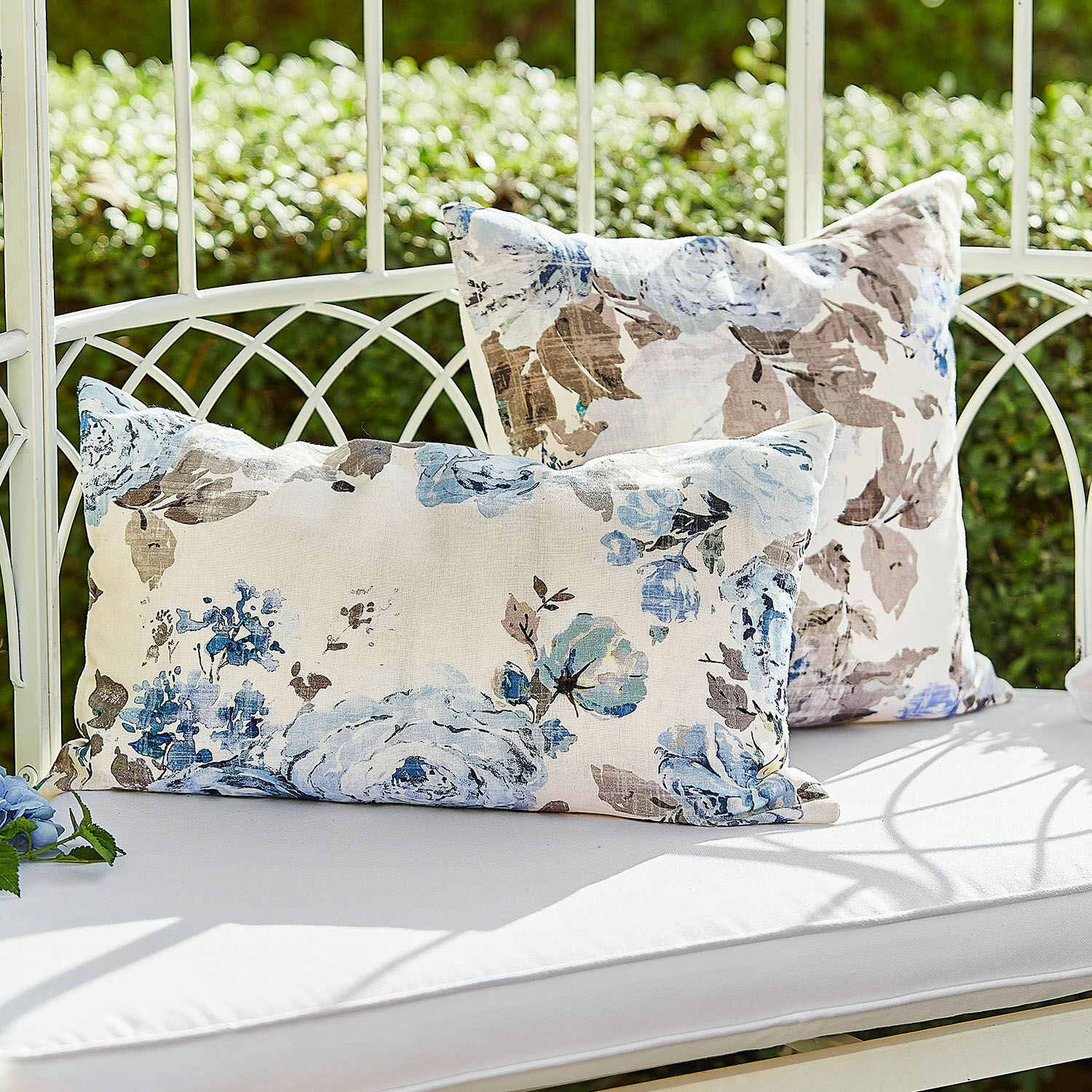 Kissenhülle 2er Set Cloranne Dekorative Baumwollkissen mit blau-braunem Blumenmuster auf weißer Gartenbank im Freien