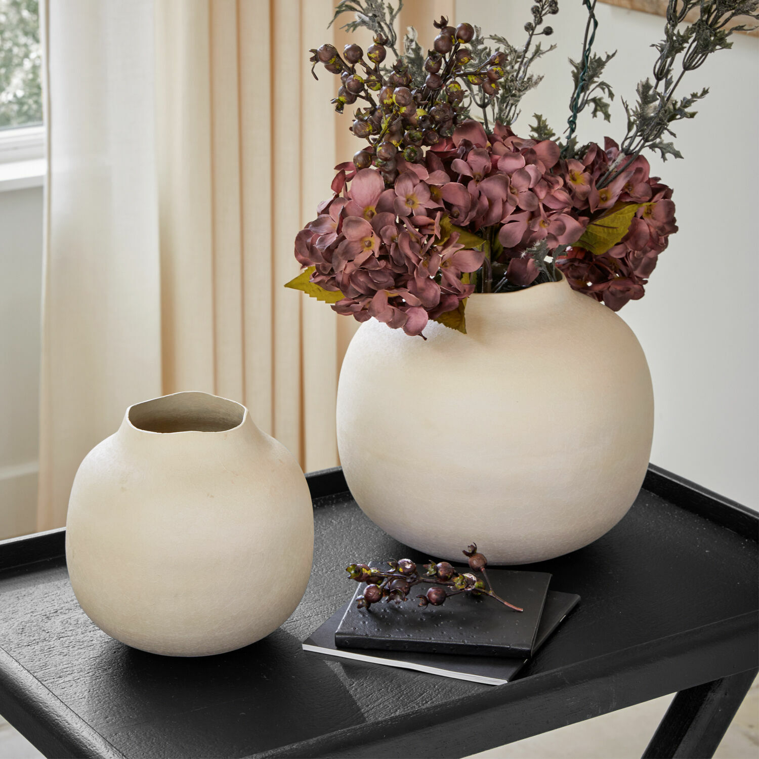 Vase 2er Set Fleurons Zwei cremefarbene Keramikvasen auf schwarzem Tisch mit dekorativen Blumen und Büchern im Hintergrund