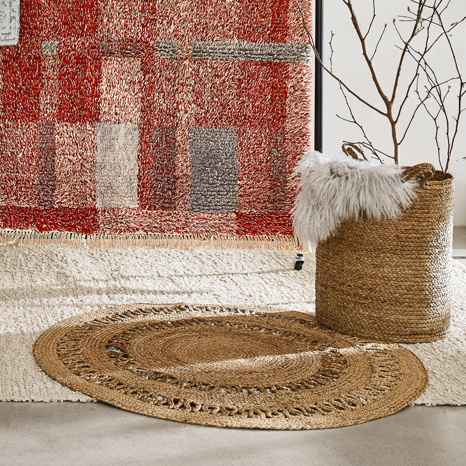 Teppich Nymarion Ovaler Jute-Teppich in Naturfarbe auf hellem Teppich mit rotem Muster im Hintergrund
