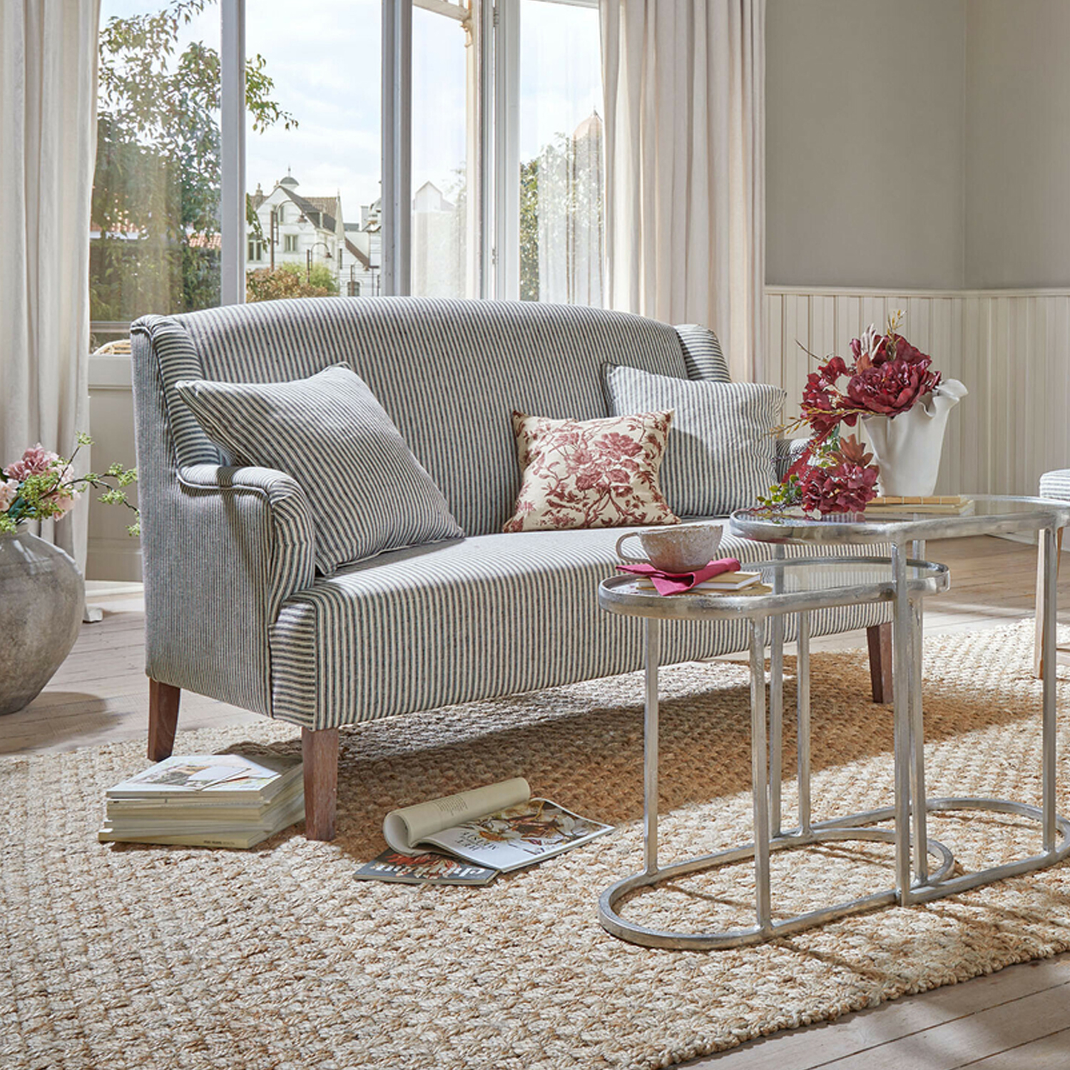 Gestreiftes Sofa aus Stoff in Grau-Weiß mit Kissen und Metall-Couchtischen in hellem Wohnzimmer