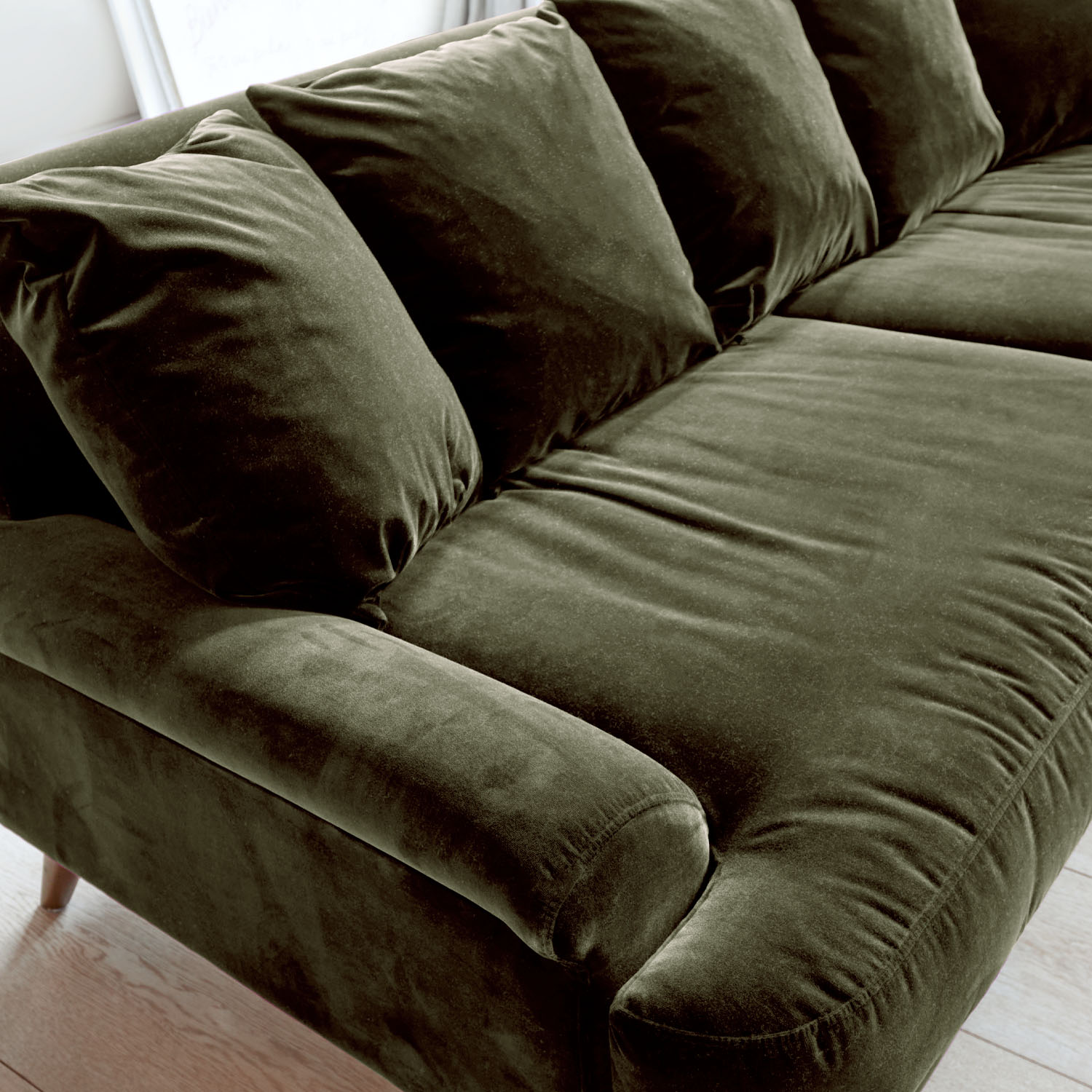 Grünes Samtsofa mit weichen Kissen und bequemen Armlehnen für das Wohnzimmer