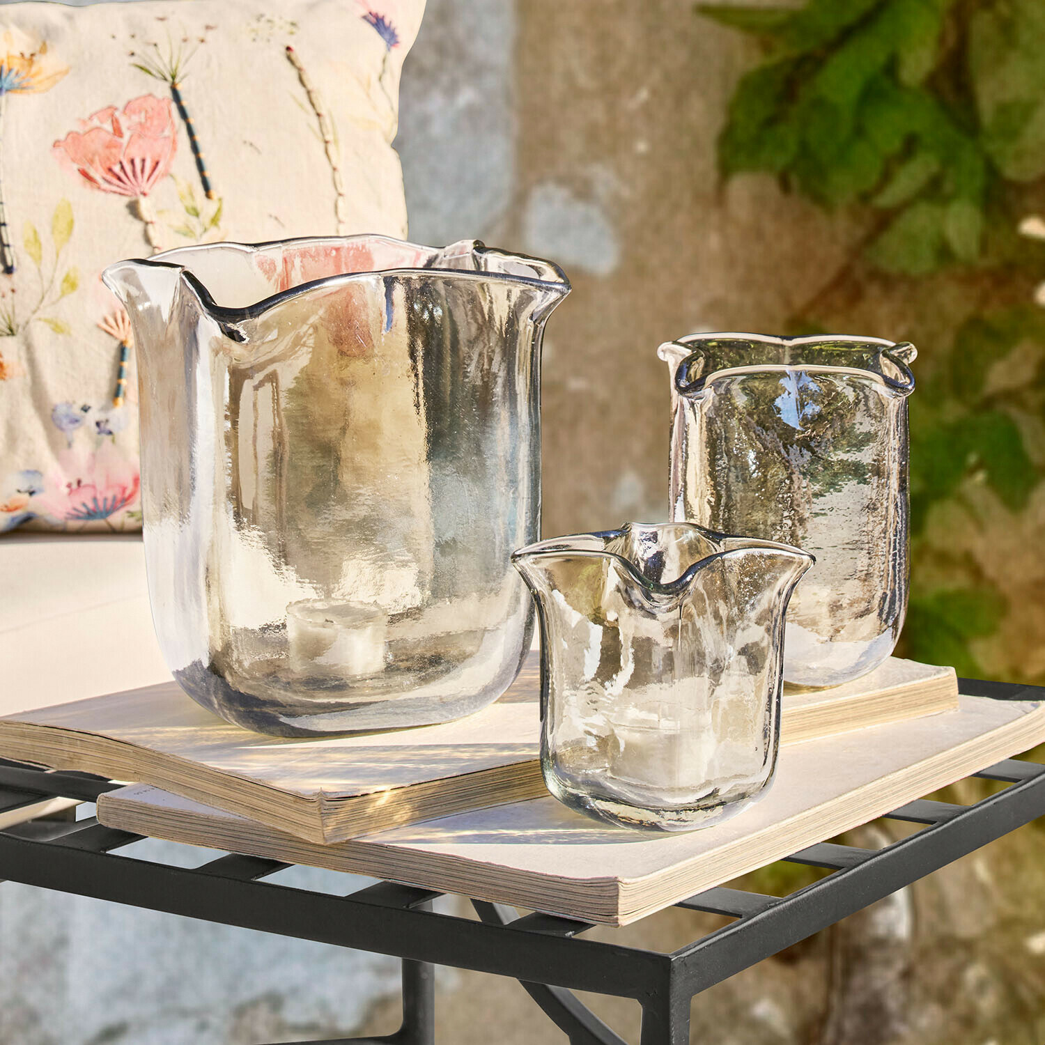 Windlicht 3er Set Ilomiane Set aus drei transparenten Glas-Teelichthaltern mit unregelmäßiger Form auf Büchern