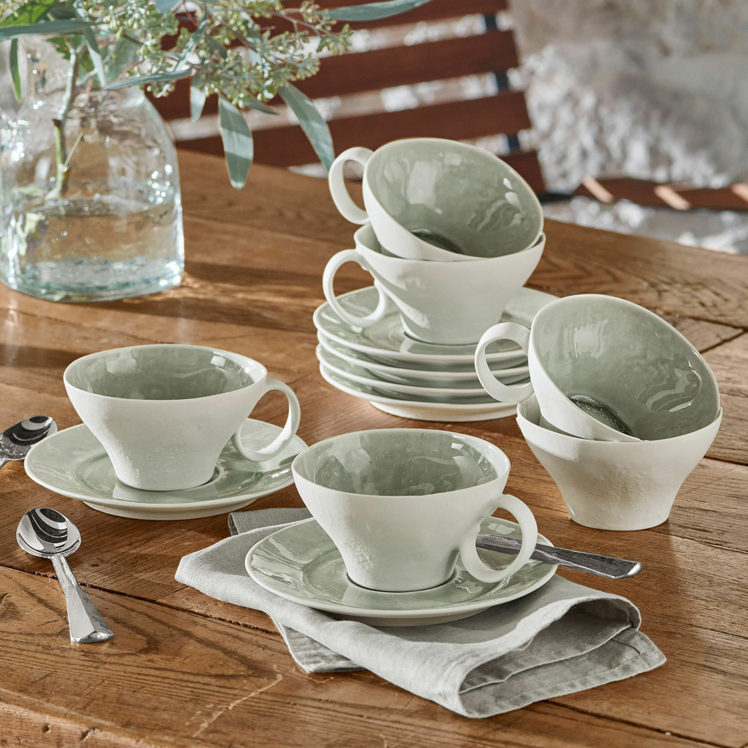 Tasse mit Untertasse 6er Set Braganza Set aus weißen Keramiktassen mit grünem Innenraum auf Holztisch mit Löffeln