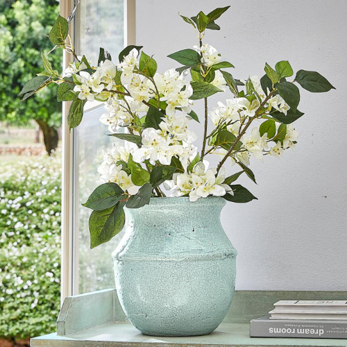 Mintgrüner Keramikvase mit weißen Blüten auf Tisch, natürliche Wohnraumdekoration