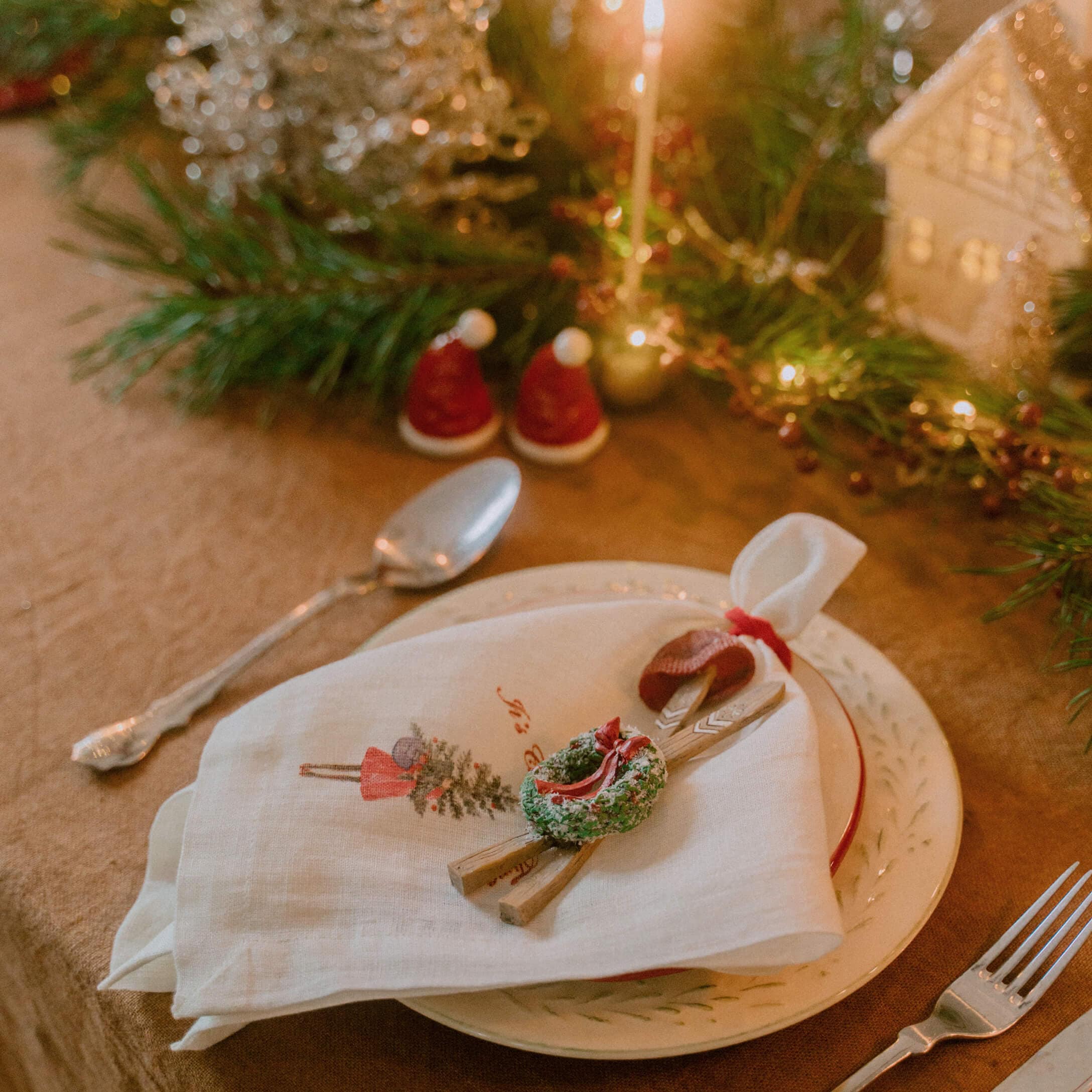 Weihnachtliche Tischdekoration mit weißer Leinenserviette und grünem Kranz auf Keramikteller