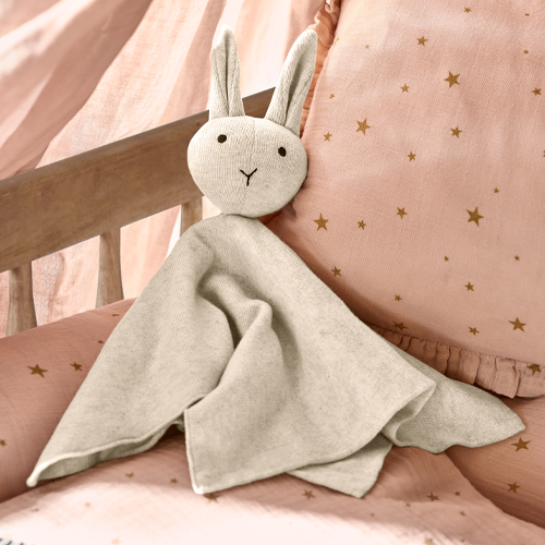 Weiches graues Stoff-Kuscheltier Hase auf rosa Bettwäsche mit Sternen, Kinderdeko